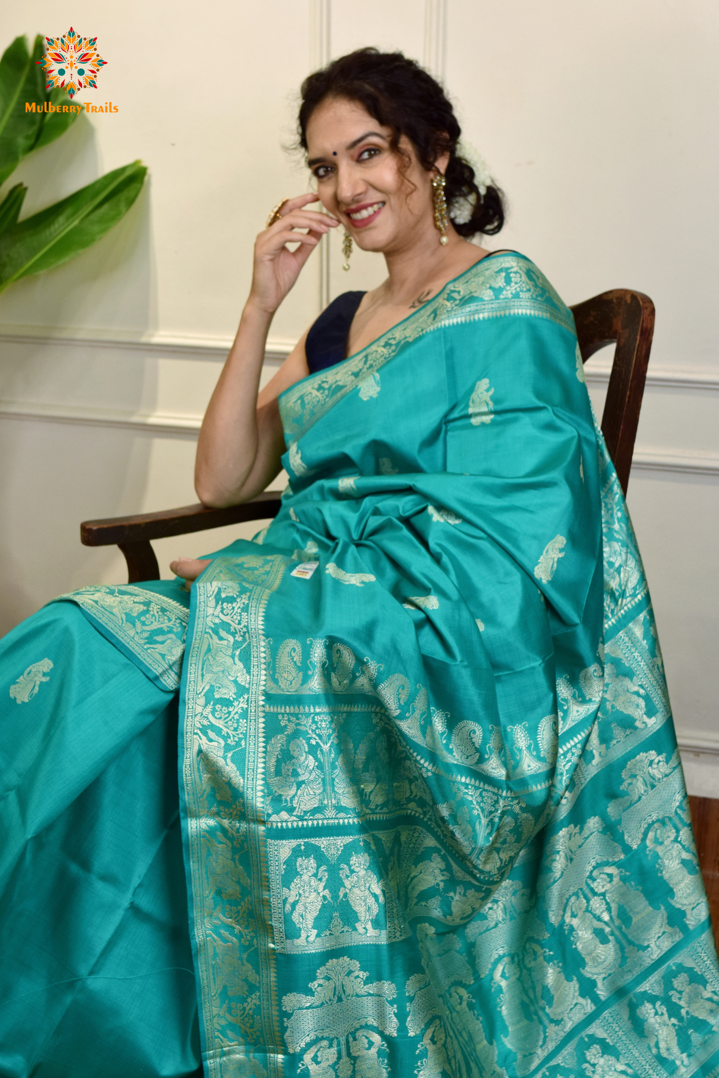 A woman wearing a Aqua Blue Baluchari Pure SIlk saree. purple baluchari silk , bengal silk saree with deer motif on pallu and ramayan, mahabharat motifs on pallu. This is a soft pure silk saree suitable for weddings, parties, festivities. suitable for Durga Puja shopping enthusiasts and diwali festival. 