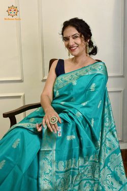 A woman wearing a Aqua Blue Baluchari Pure SIlk saree. purple baluchari silk , bengal silk saree with deer motif on pallu and ramayan, mahabharat motifs on pallu. This is a soft pure silk saree suitable for weddings, parties, festivities. suitable for Durga Puja shopping enthusiasts and diwali festival. 