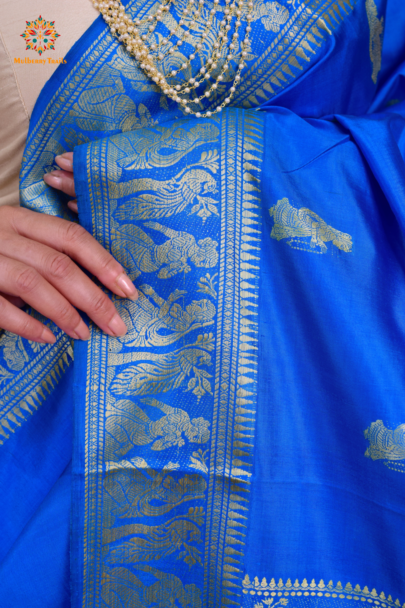 A woman wearing a Blue Baluchari Pure SIlk saree. Blue baluchari silk , bengal silk saree with deer motif on pallu and ramayan, mahabharat motifs on pallu. This is a soft pure silk saree suitable for weddings, parties, festivities. suitable for Durga Puja shopping enthusiasts and diwali festival. 