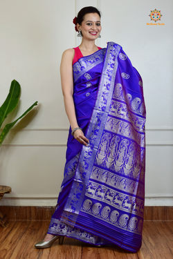 A woman wearing a Purple Baluchari Pure SIlk saree. Purple baluchari silk , bengal silk saree with deer motif on pallu and ramayan, mahabharat motifs on pallu. This is a soft pure silk saree suitable for weddings, parties, festivities. suitable for Durga Puja shopping enthusiasts and diwali festival. 