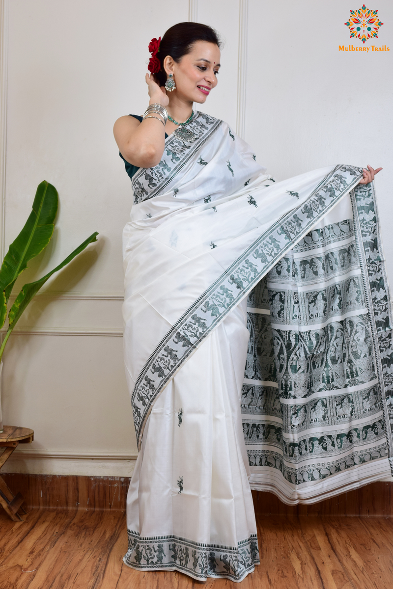 A woman wearing a White Baluchari Pure SIlk saree. White baluchari silk , bengal silk saree with deer motif on pallu and ramayan, mahabharat motifs on pallu. This is a soft pure silk saree suitable for weddings, parties, festivities. suitable for Durga Puja shopping enthusiasts and diwali festival. 