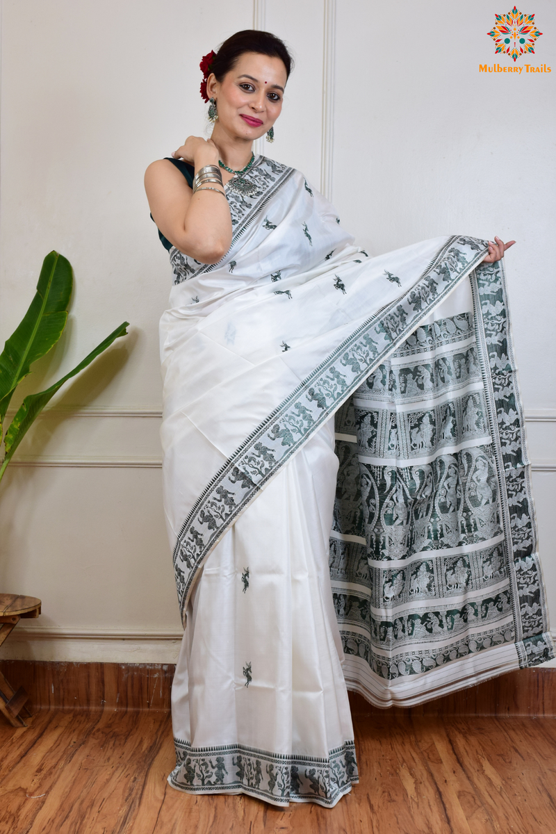 A woman wearing a White Baluchari Pure SIlk saree. White baluchari silk , bengal silk saree with deer motif on pallu and ramayan, mahabharat motifs on pallu. This is a soft pure silk saree suitable for weddings, parties, festivities. suitable for Durga Puja shopping enthusiasts and diwali festival. 