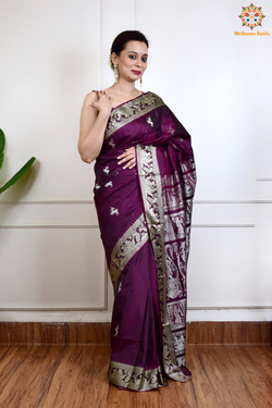 A woman wearing a Purple Baluchari Pure SIlk saree. Purple baluchari silk , bengal silk saree with deer motif on pallu and ramayan, mahabharat motifs on pallu. This is a soft pure silk saree suitable for weddings, parties, festivities. suitable for Durga Puja shopping enthusiasts and diwali festival. 