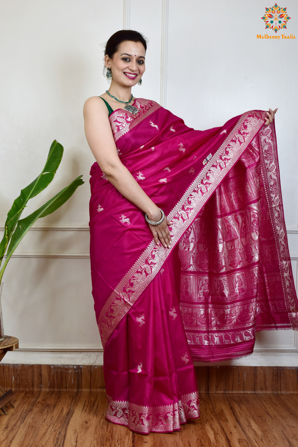 A woman wearing a Pink Baluchari Pure SIlk saree. Pink baluchari silk , bengal silk saree with deer motif on pallu and ramayan, mahabharat motifs on pallu. This is a soft pure silk saree suitable for weddings, parties, festivities. suitable for Durga Puja shopping enthusiasts and diwali festival. 