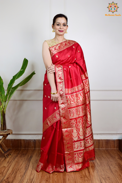 A woman wearing a Red Baluchari Pure SIlk saree. Red baluchari silk , bengal silk saree with deer motif on pallu and ramayan, mahabharat motifs on pallu. This is a soft pure silk saree suitable for weddings, parties, festivities. suitable for Durga Puja shopping enthusiasts and diwali festival. 