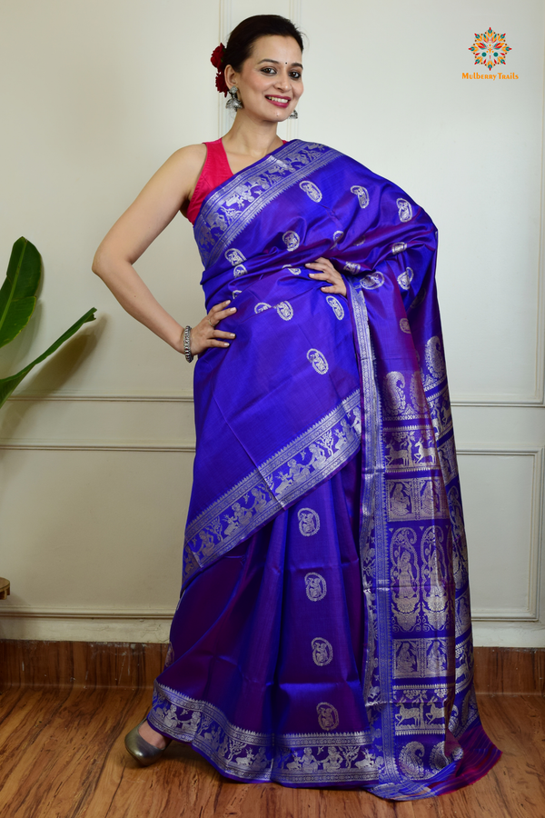 A woman wearing a Purple Baluchari Pure SIlk saree. Purple baluchari silk , bengal silk saree with deer motif on pallu and ramayan, mahabharat motifs on pallu. This is a soft pure silk saree suitable for weddings, parties, festivities. suitable for Durga Puja shopping enthusiasts and diwali festival. 