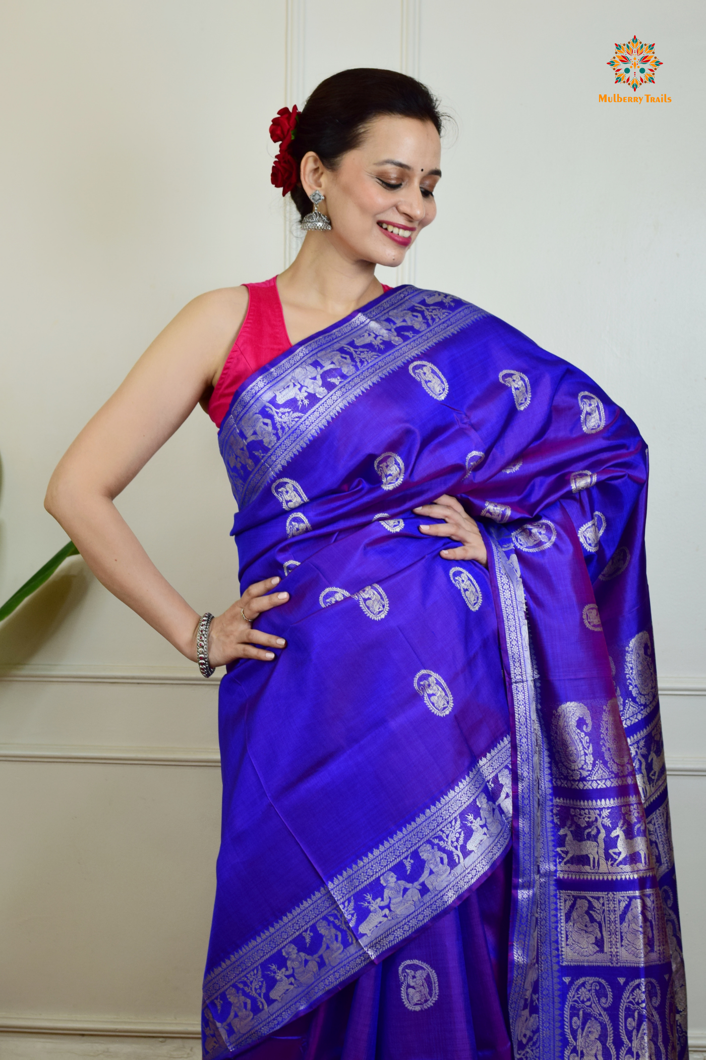 A woman wearing a Purple Baluchari Pure SIlk saree. Purple baluchari silk , bengal silk saree with deer motif on pallu and ramayan, mahabharat motifs on pallu. This is a soft pure silk saree suitable for weddings, parties, festivities. suitable for Durga Puja shopping enthusiasts and diwali festival. 