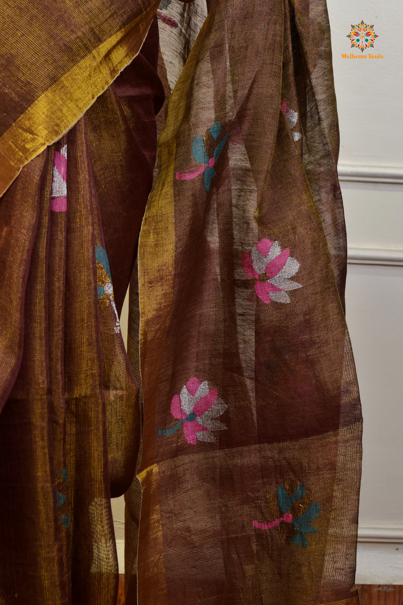 This image features an Elegant tissue saree featuring intricate handwoven Jamdani lotus motifs, with a lightweight, shimmery fabric that drapes beautifully, perfect for festive and special occasions. Party wear , diwali theme. 