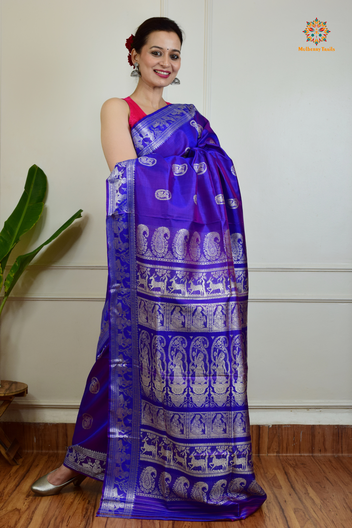 A woman wearing a Purple Baluchari Pure SIlk saree. Purple baluchari silk , bengal silk saree with deer motif on pallu and ramayan, mahabharat motifs on pallu. This is a soft pure silk saree suitable for weddings, parties, festivities. suitable for Durga Puja shopping enthusiasts and diwali festival. 