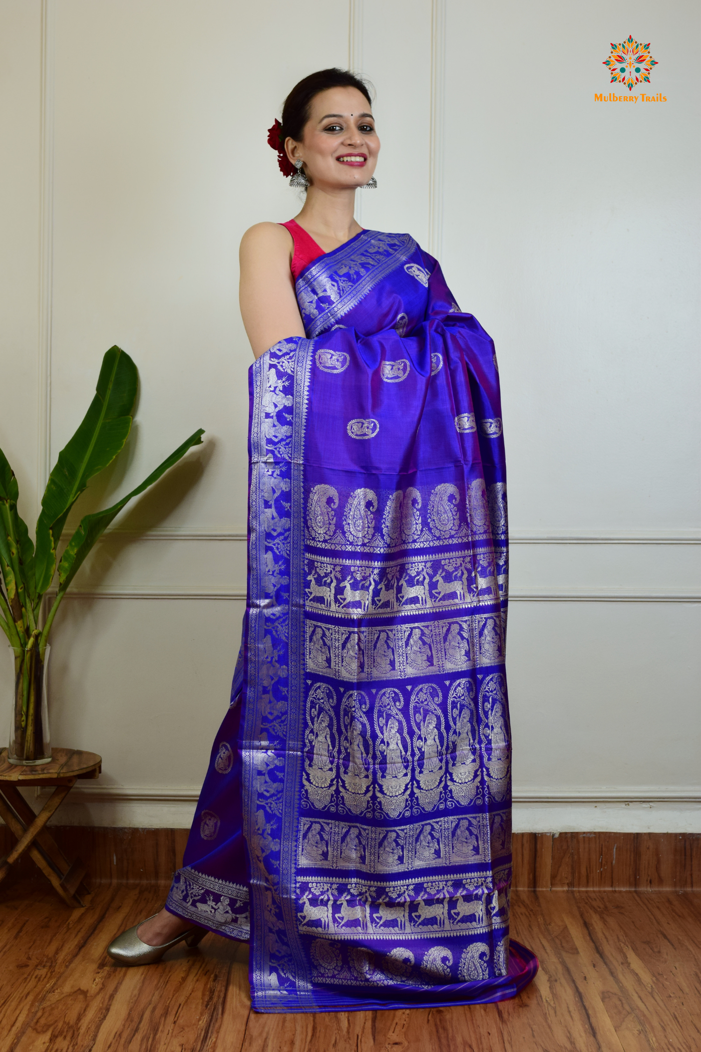 A woman wearing a Purple Baluchari Pure SIlk saree. Purple baluchari silk , bengal silk saree with deer motif on pallu and ramayan, mahabharat motifs on pallu. This is a soft pure silk saree suitable for weddings, parties, festivities. suitable for Durga Puja shopping enthusiasts and diwali festival. 