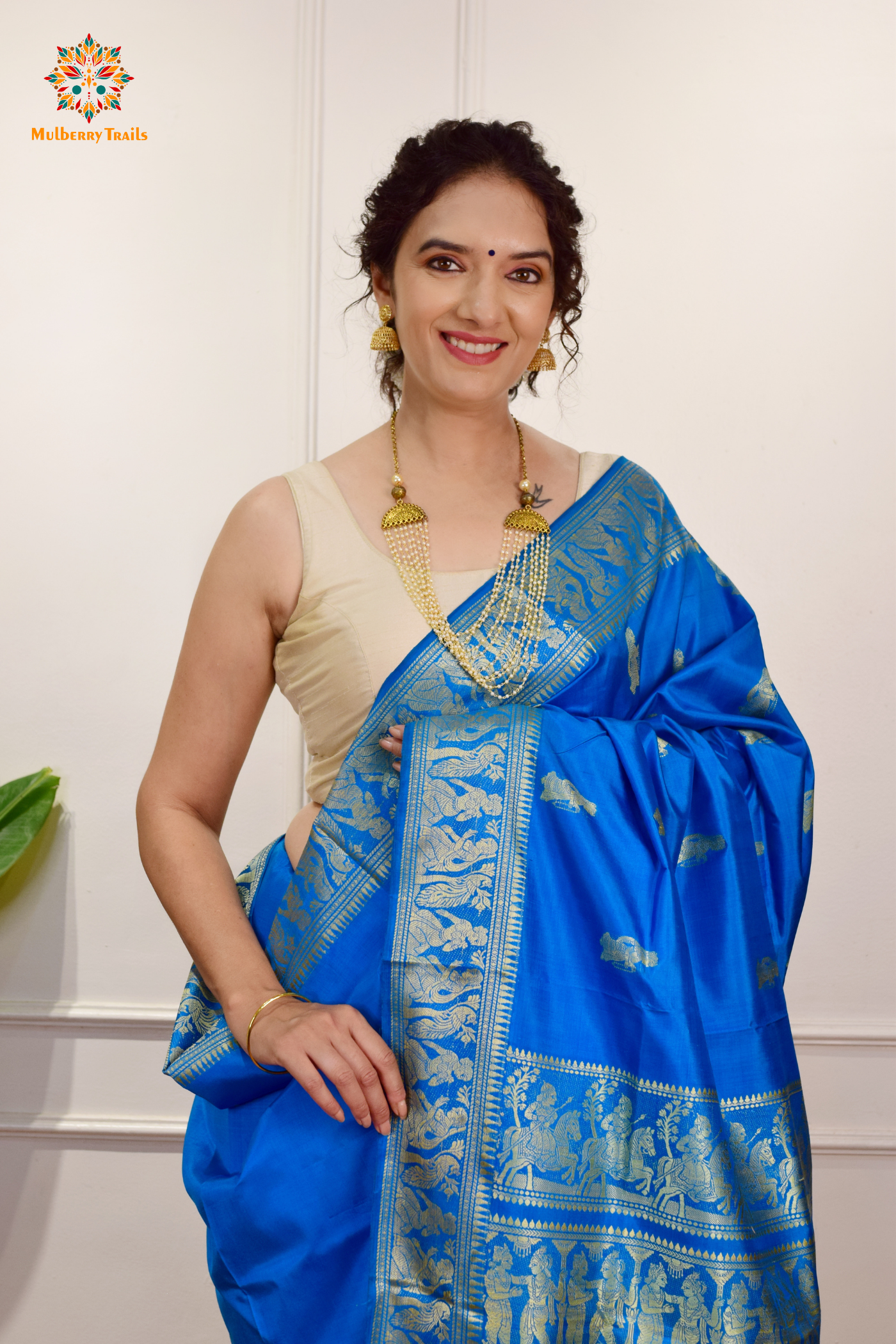 A woman wearing a Blue Baluchari Pure SIlk saree. Blue baluchari silk , bengal silk saree with deer motif on pallu and ramayan, mahabharat motifs on pallu. This is a soft pure silk saree suitable for weddings, parties, festivities. suitable for Durga Puja shopping enthusiasts and diwali festival. 