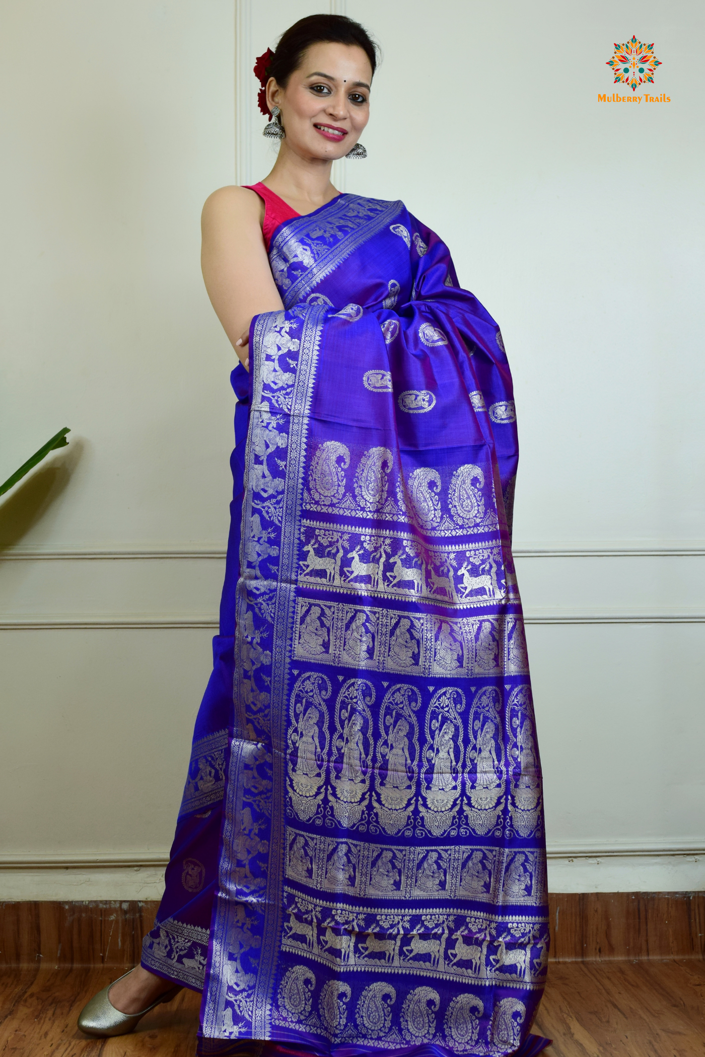 A woman wearing a Purple Baluchari Pure SIlk saree. Purple baluchari silk , bengal silk saree with deer motif on pallu and ramayan, mahabharat motifs on pallu. This is a soft pure silk saree suitable for weddings, parties, festivities. suitable for Durga Puja shopping enthusiasts and diwali festival. 