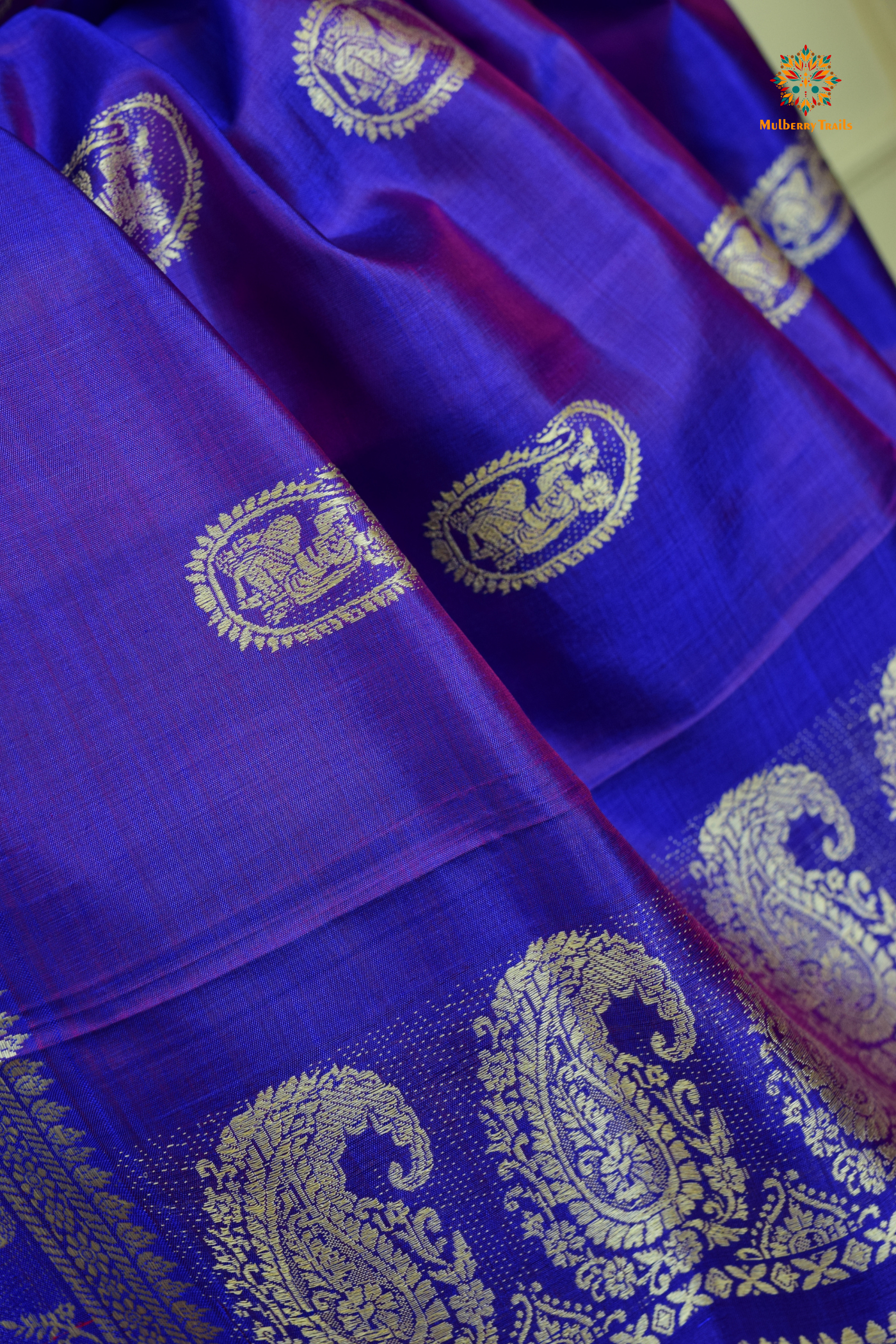 A woman wearing a Purple Baluchari Pure SIlk saree. Purple baluchari silk , bengal silk saree with deer motif on pallu and ramayan, mahabharat motifs on pallu. This is a soft pure silk saree suitable for weddings, parties, festivities. suitable for Durga Puja shopping enthusiasts and diwali festival. 