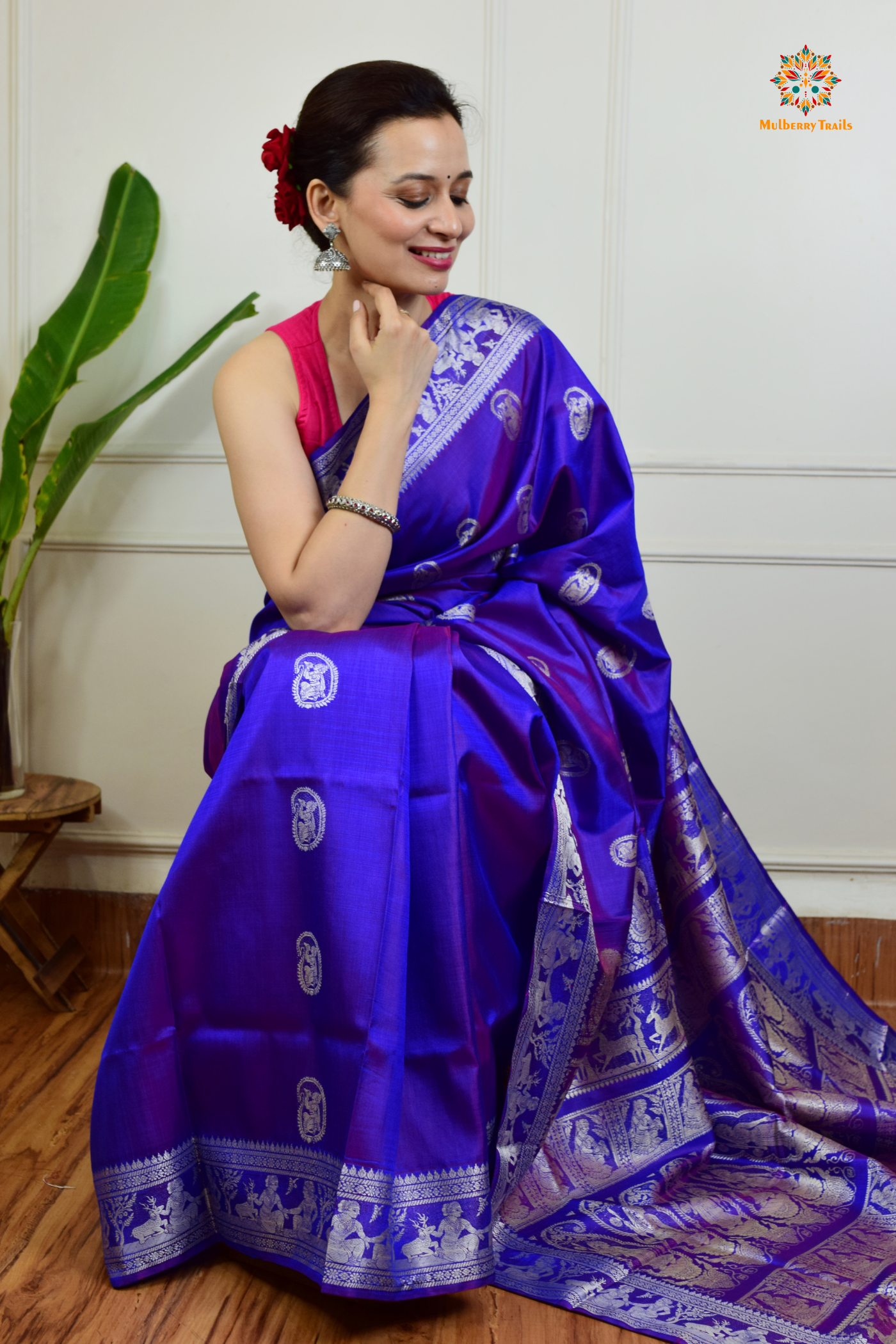 A woman wearing a Purple Baluchari Pure SIlk saree. Purple baluchari silk , bengal silk saree with deer motif on pallu and ramayan, mahabharat motifs on pallu. This is a soft pure silk saree suitable for weddings, parties, festivities. suitable for Durga Puja shopping enthusiasts and diwali festival. 