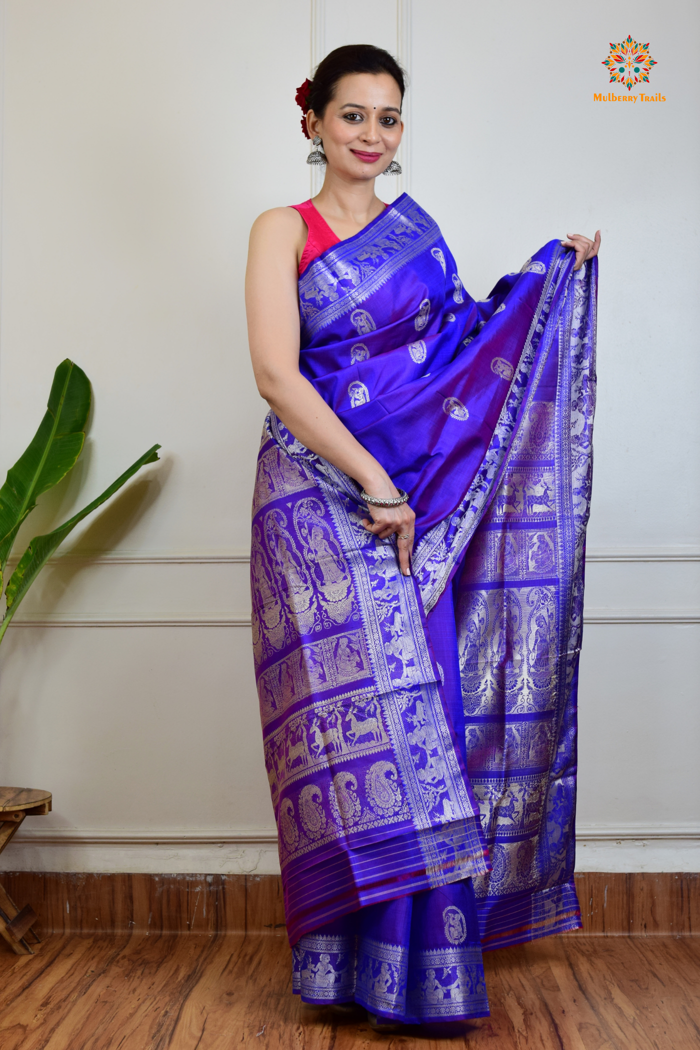 A woman wearing a Purple Baluchari Pure SIlk saree. Purple baluchari silk , bengal silk saree with deer motif on pallu and ramayan, mahabharat motifs on pallu. This is a soft pure silk saree suitable for weddings, parties, festivities. suitable for Durga Puja shopping enthusiasts and diwali festival. 