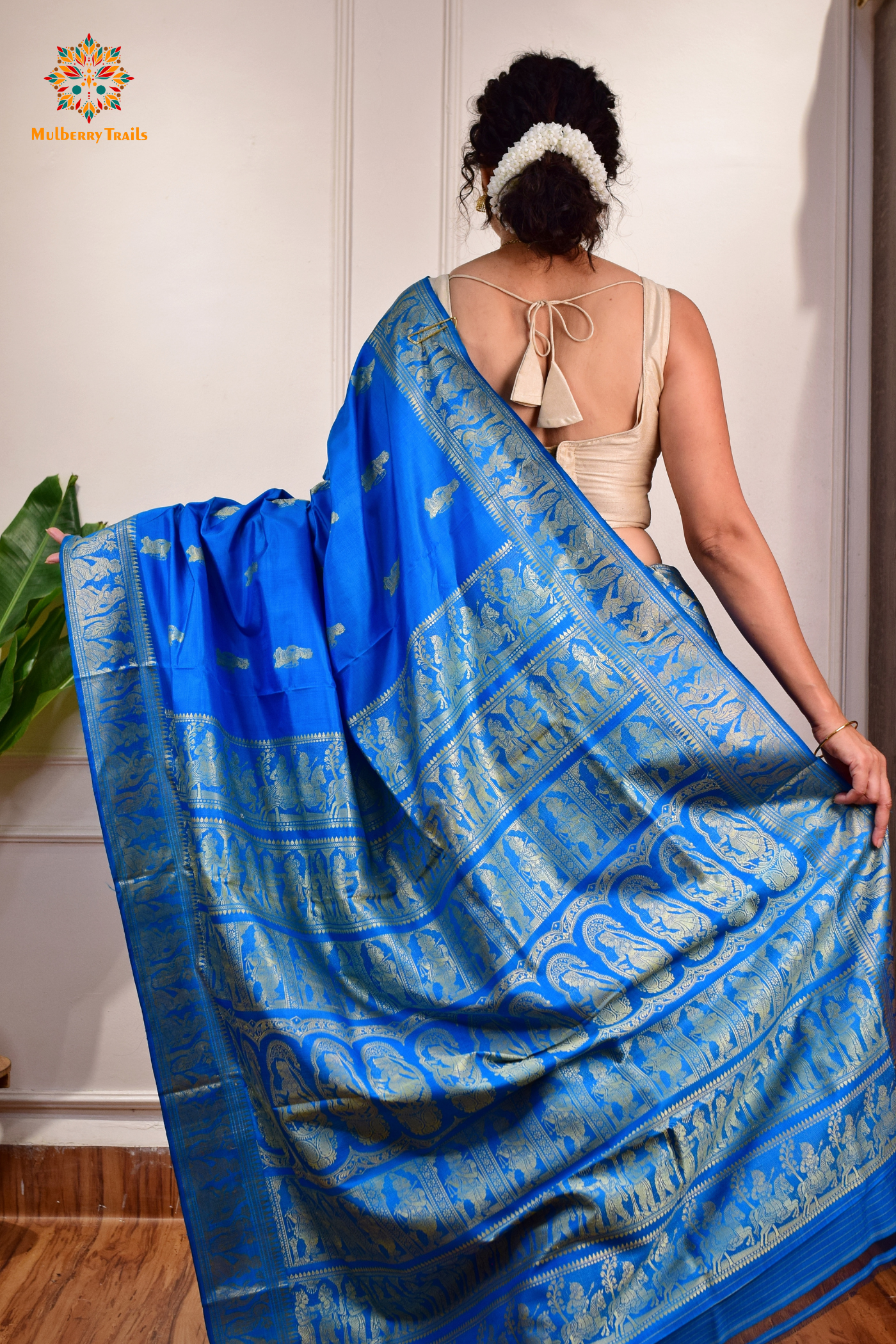 A woman wearing a Blue Baluchari Pure SIlk saree. Blue baluchari silk , bengal silk saree with deer motif on pallu and ramayan, mahabharat motifs on pallu. This is a soft pure silk saree suitable for weddings, parties, festivities. suitable for Durga Puja shopping enthusiasts and diwali festival. 