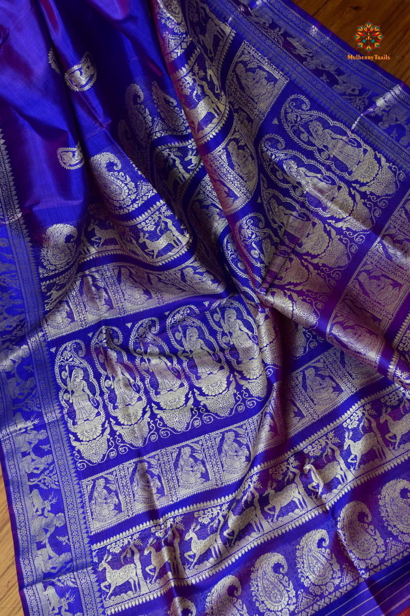 A woman wearing a Purple Baluchari Pure SIlk saree. Purple baluchari silk , bengal silk saree with deer motif on pallu and ramayan, mahabharat motifs on pallu. This is a soft pure silk saree suitable for weddings, parties, festivities. suitable for Durga Puja shopping enthusiasts and diwali festival. 