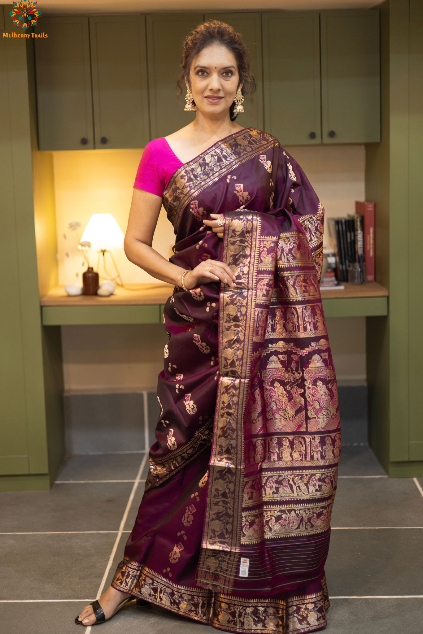 Woman wearing a purple saree with a pattern in a room. Woman in a wine saree standing in a elegant setting. 
Swarnachari – Pure Silk Meenakari Saree

1. “Pure silk Swarnachari saree with meenakari motif weave and gold copper zari detailing for a regal look.”

2. “Silk Mark pure silk meenakari saree featuring intricate copper gold zari motifs and rich texture.” 
Woman wearing a wine color swarnachari saree in a room with a desk and lamp.