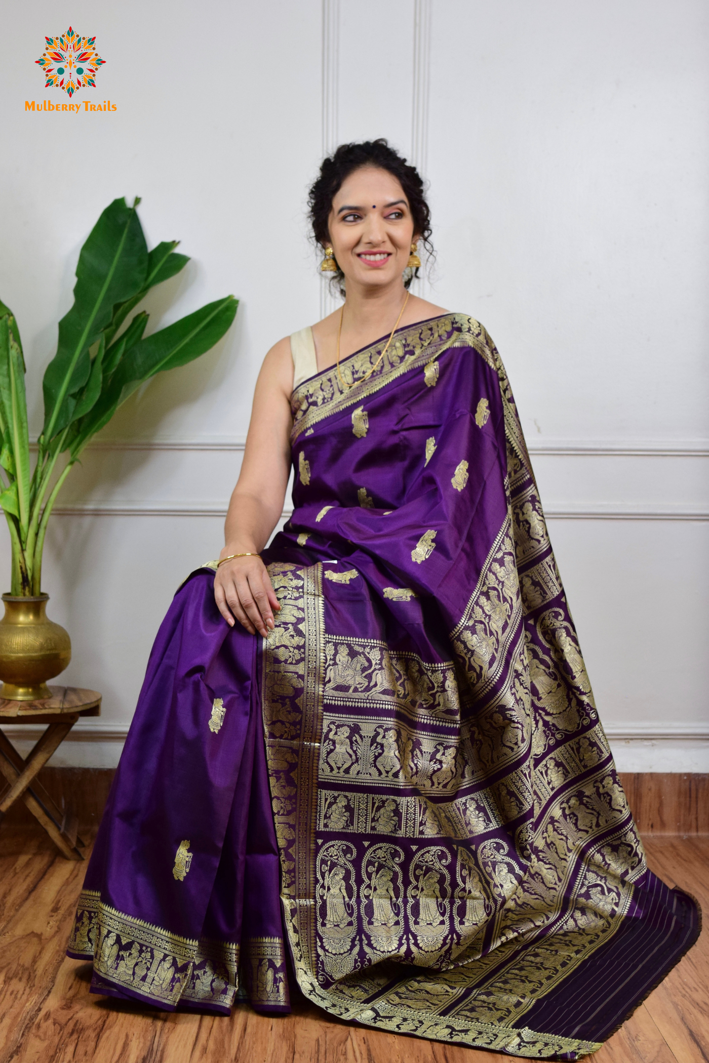 A woman wearing a Purple Baluchari Pure SIlk saree. purple baluchari silk , bengal silk saree with deer motif on pallu and ramayan, mahabharat motifs on pallu. This is a soft pure silk saree suitable for weddings, parties, festivities. suitable for Durga Puja shopping enthusiasts and diwali festival. 