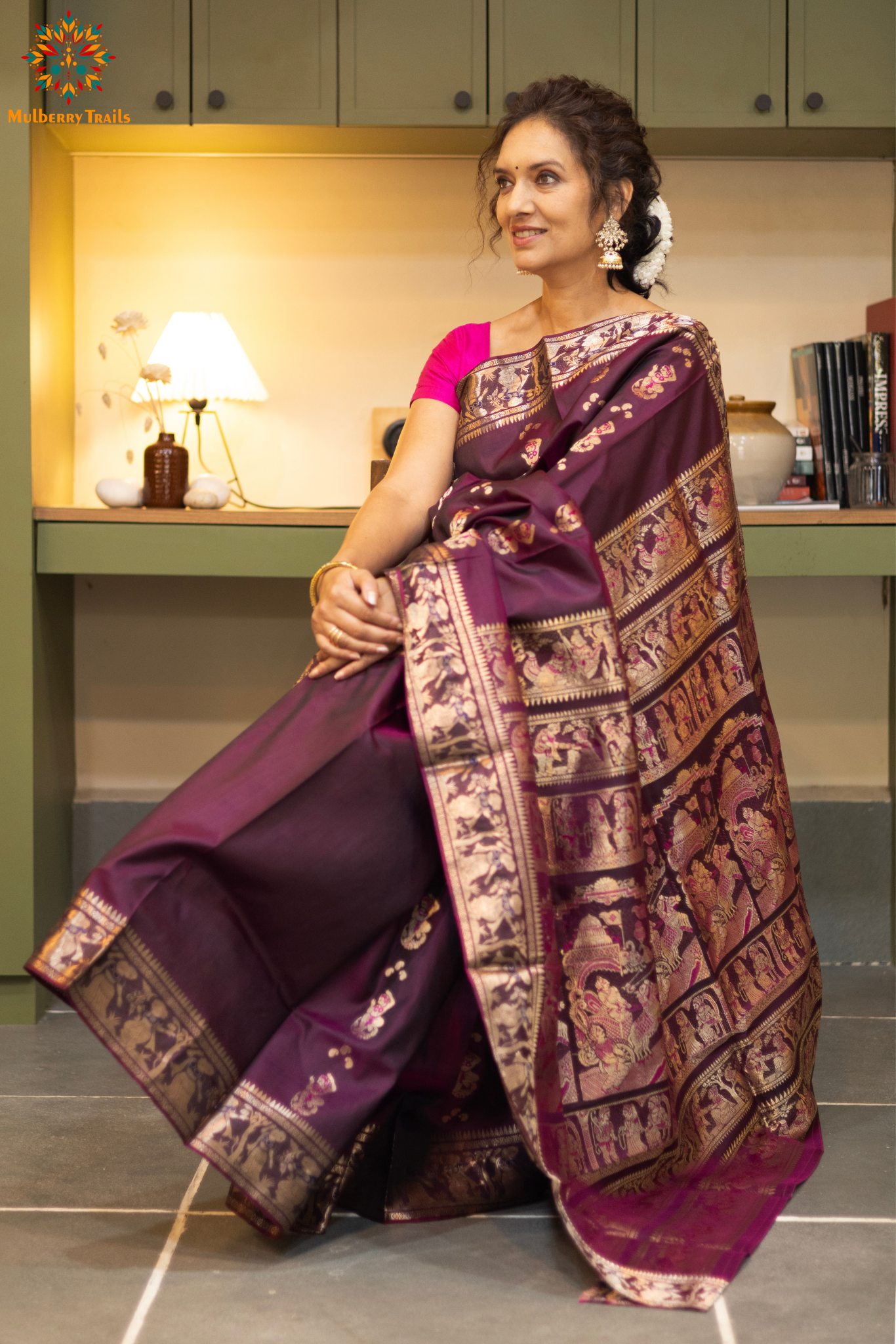Woman wearing a purple saree with a pattern in a room. Woman in a wine saree standing in a elegant setting. 
Swarnachari – Pure Silk Meenakari Saree

1. “Pure silk Swarnachari saree with meenakari motif weave and gold copper zari detailing for a regal look.”

2. “Silk Mark pure silk meenakari saree featuring intricate copper gold zari motifs and rich texture.” 
Woman wearing a wine color swarnachari saree in a room with a desk and lamp.
