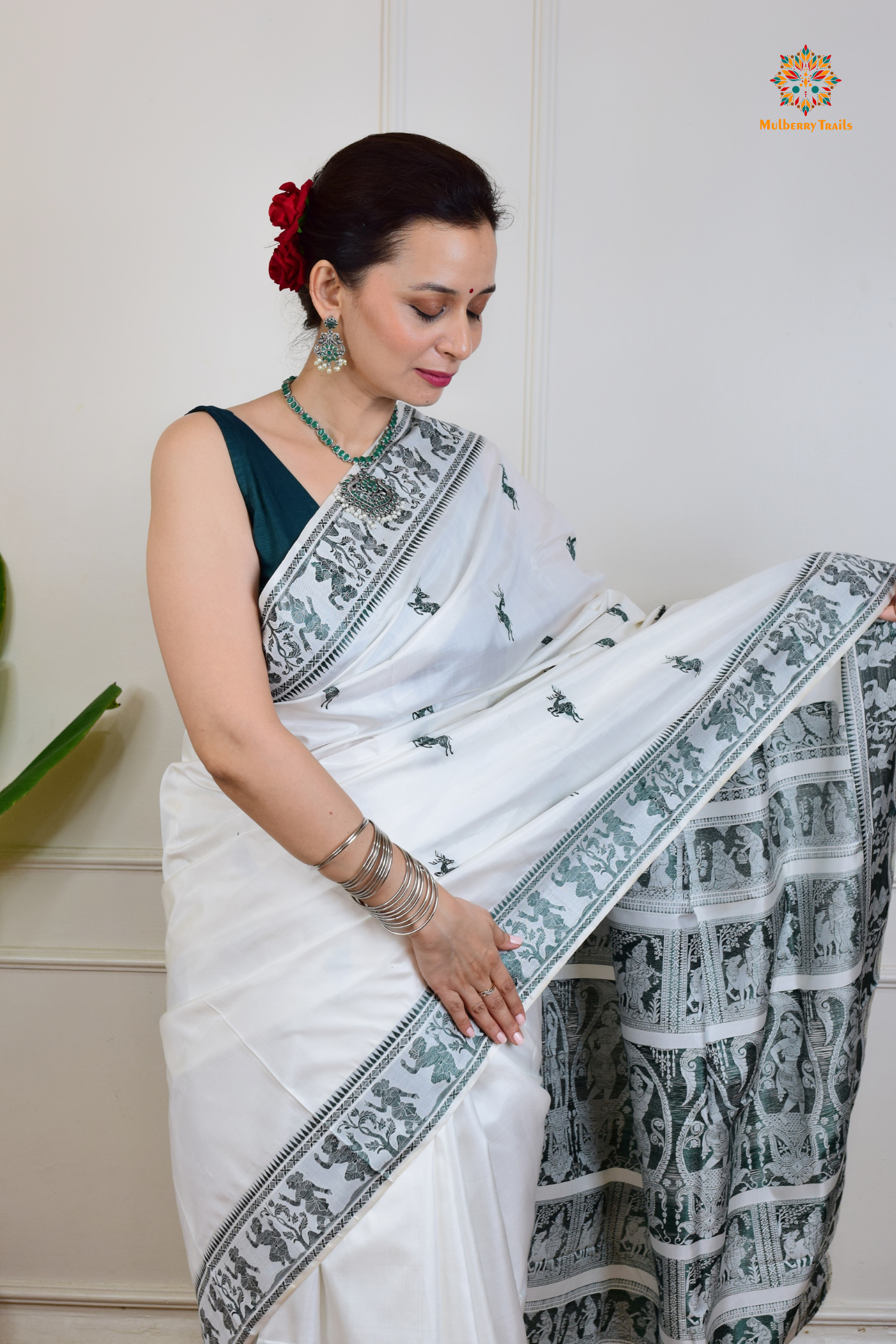 A woman wearing a White Baluchari Pure SIlk saree. White baluchari silk , bengal silk saree with deer motif on pallu and ramayan, mahabharat motifs on pallu. This is a soft pure silk saree suitable for weddings, parties, festivities. suitable for Durga Puja shopping enthusiasts and diwali festival. 