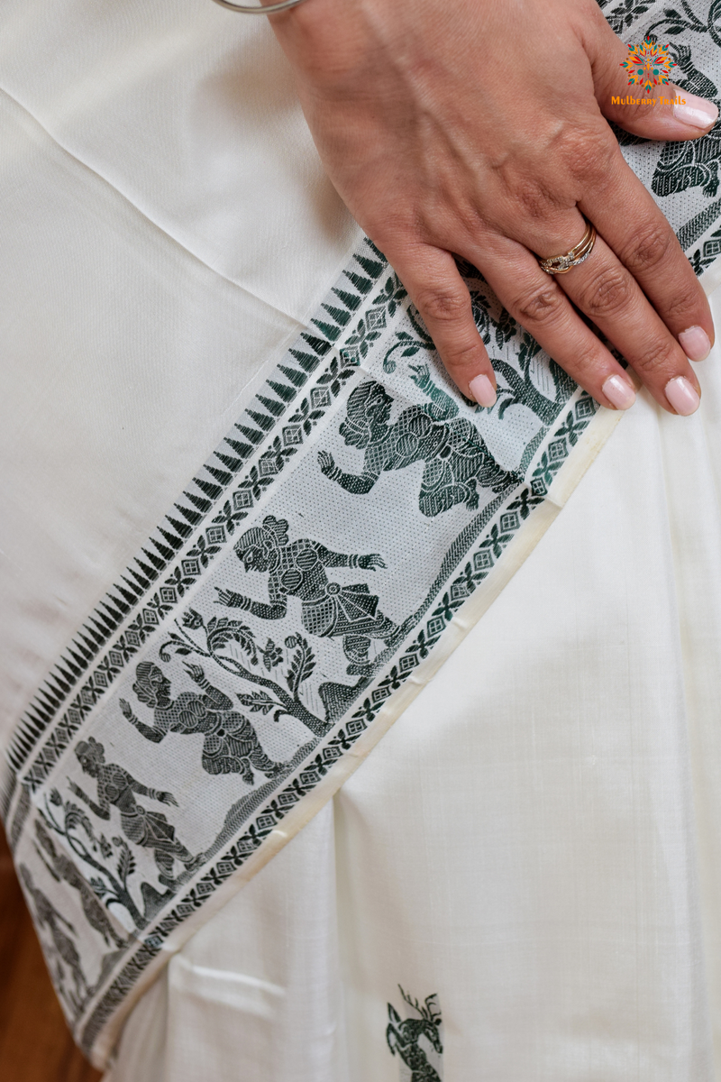 A woman wearing a White Baluchari Pure SIlk saree. White baluchari silk , bengal silk saree with deer motif on pallu and ramayan, mahabharat motifs on pallu. This is a soft pure silk saree suitable for weddings, parties, festivities. suitable for Durga Puja shopping enthusiasts and diwali festival. 