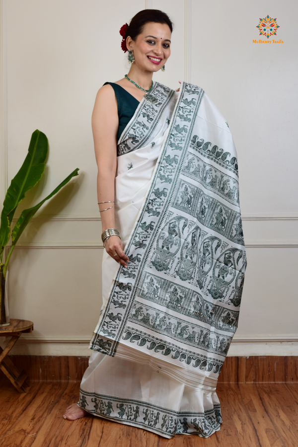 A woman wearing a White Baluchari Pure SIlk saree. White baluchari silk , bengal silk saree with deer motif on pallu and ramayan, mahabharat motifs on pallu. This is a soft pure silk saree suitable for weddings, parties, festivities. suitable for Durga Puja shopping enthusiasts and diwali festival. 