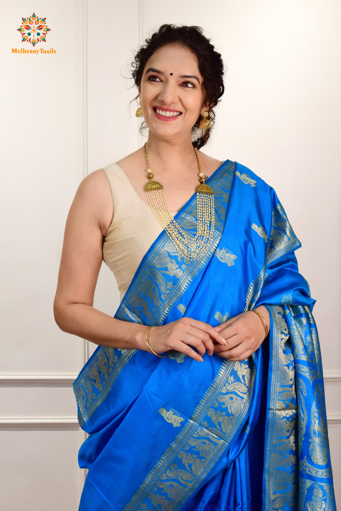 A woman wearing a Blue Baluchari Pure SIlk saree. Blue baluchari silk , bengal silk saree with deer motif on pallu and ramayan, mahabharat motifs on pallu. This is a soft pure silk saree suitable for weddings, parties, festivities. suitable for Durga Puja shopping enthusiasts and diwali festival. 