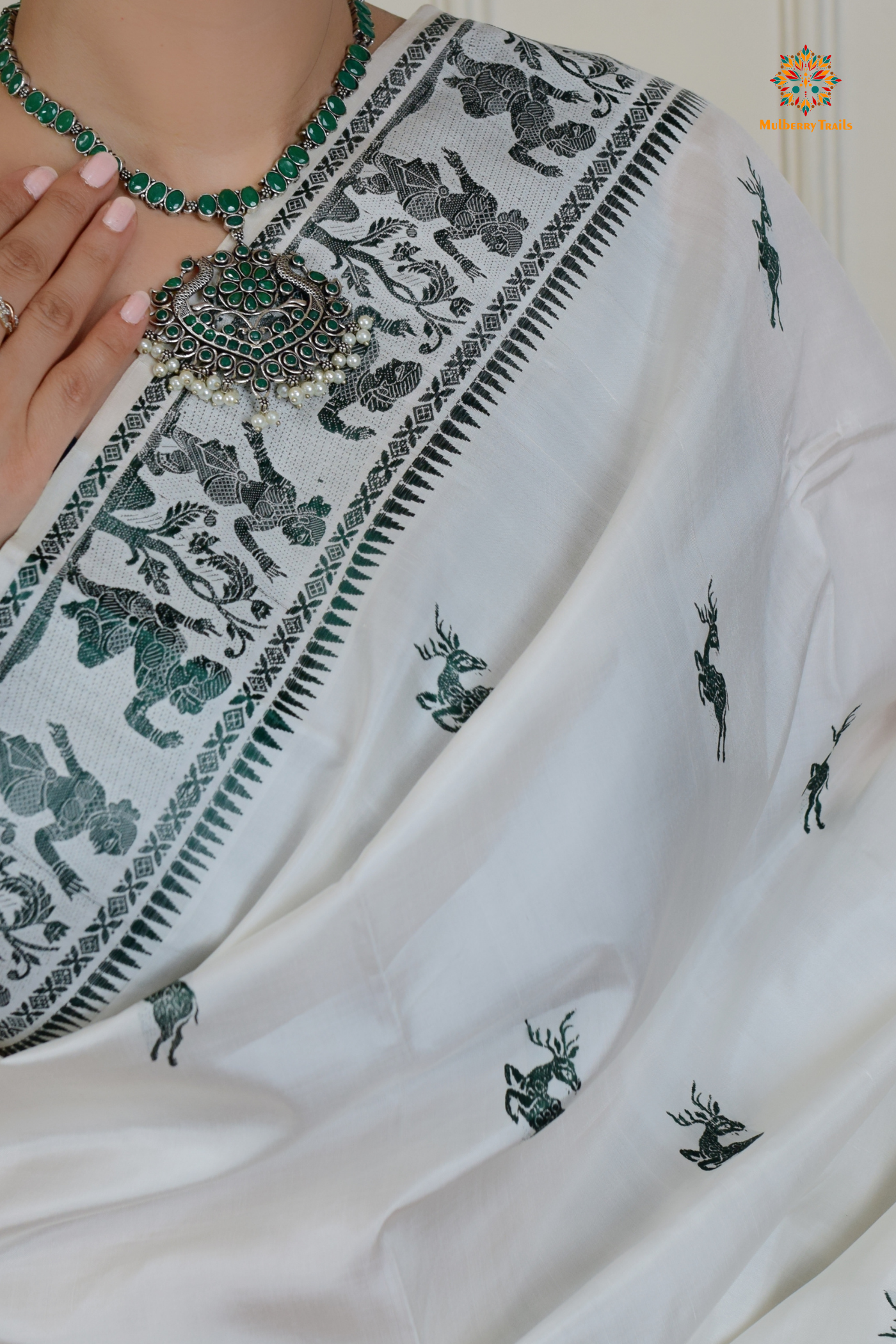 A woman wearing a White Baluchari Pure SIlk saree. White baluchari silk , bengal silk saree with deer motif on pallu and ramayan, mahabharat motifs on pallu. This is a soft pure silk saree suitable for weddings, parties, festivities. suitable for Durga Puja shopping enthusiasts and diwali festival. 