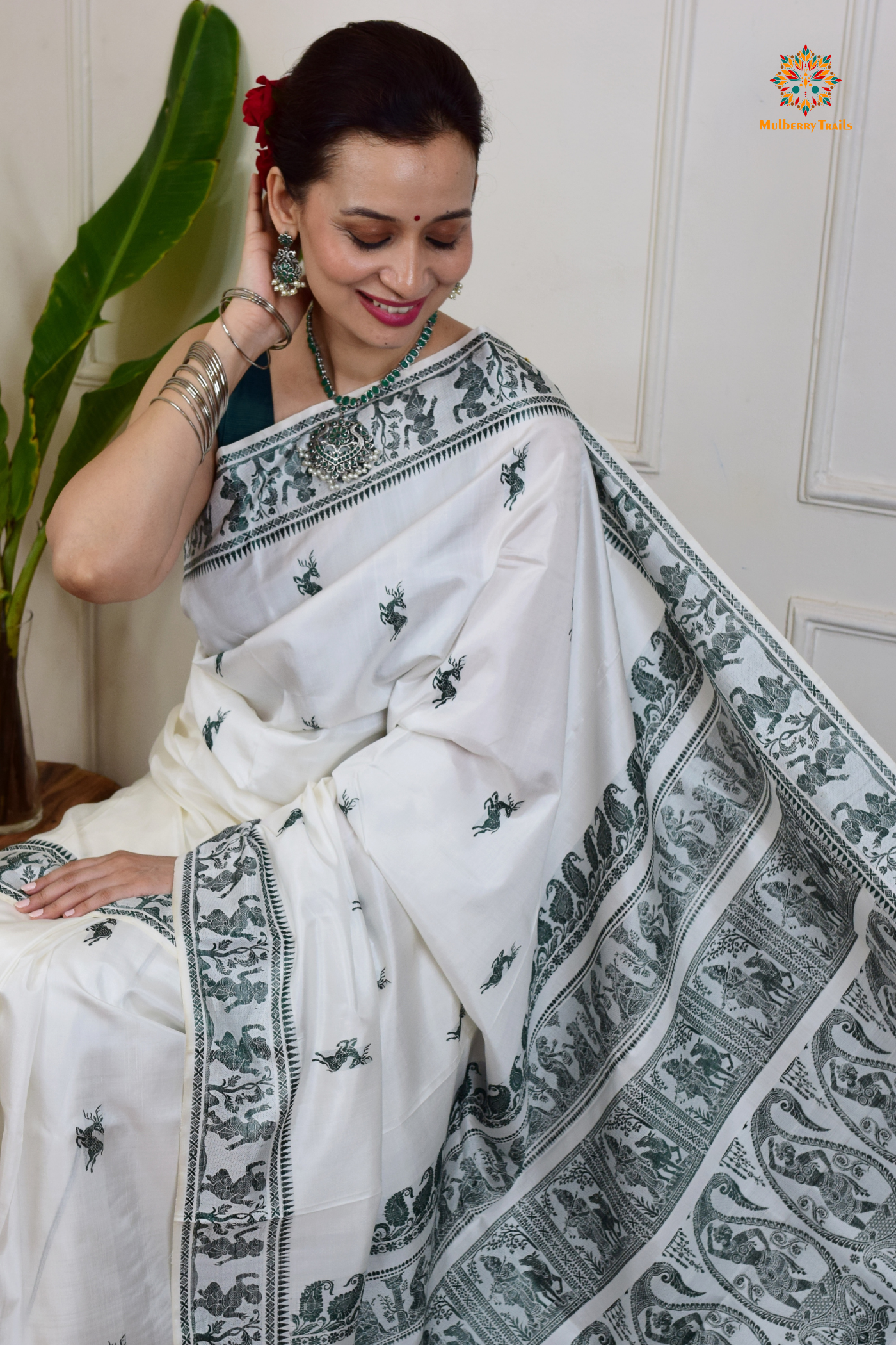 A woman wearing a White Baluchari Pure SIlk saree. White baluchari silk , bengal silk saree with deer motif on pallu and ramayan, mahabharat motifs on pallu. This is a soft pure silk saree suitable for weddings, parties, festivities. suitable for Durga Puja shopping enthusiasts and diwali festival. 