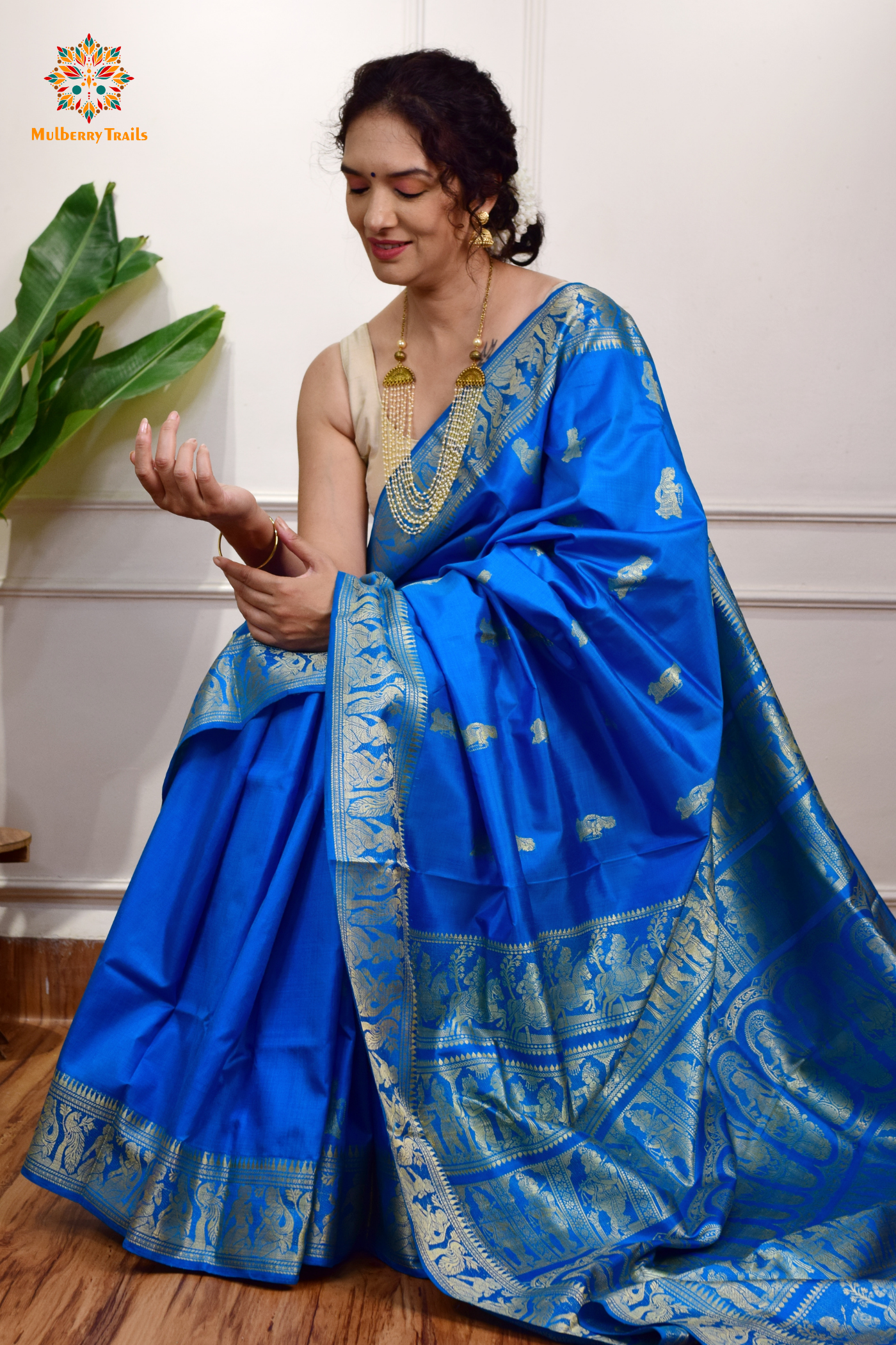 A woman wearing a Blue Baluchari Pure SIlk saree. Blue baluchari silk , bengal silk saree with deer motif on pallu and ramayan, mahabharat motifs on pallu. This is a soft pure silk saree suitable for weddings, parties, festivities. suitable for Durga Puja shopping enthusiasts and diwali festival. 