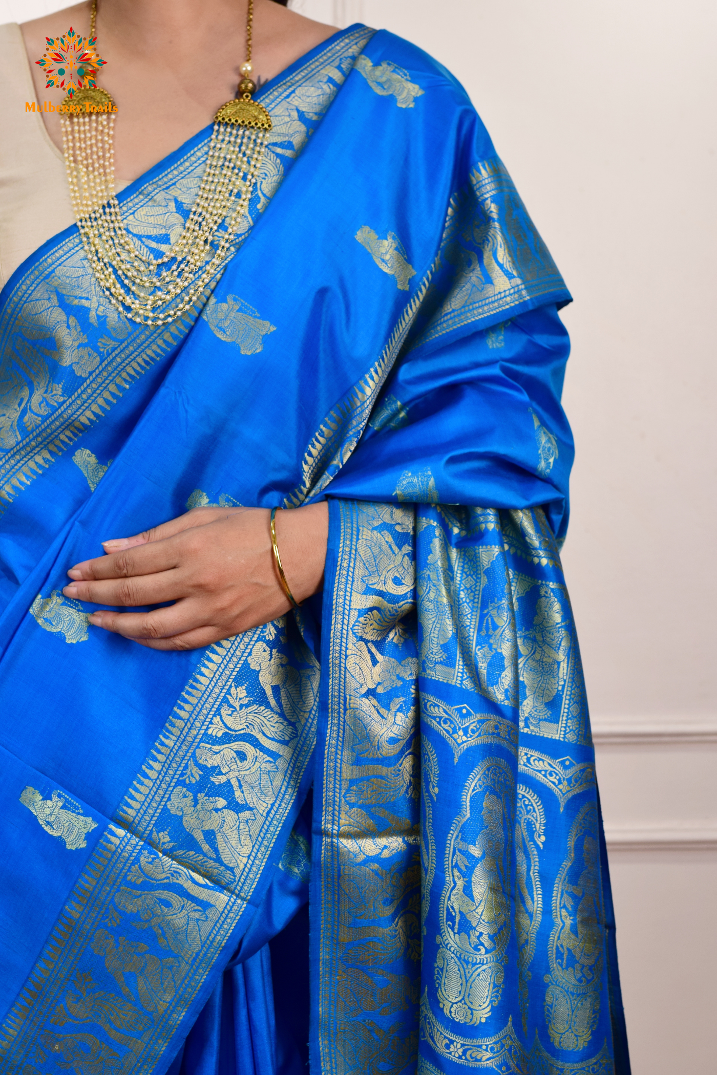 A woman wearing a Blue Baluchari Pure SIlk saree. Blue baluchari silk , bengal silk saree with deer motif on pallu and ramayan, mahabharat motifs on pallu. This is a soft pure silk saree suitable for weddings, parties, festivities. suitable for Durga Puja shopping enthusiasts and diwali festival. 