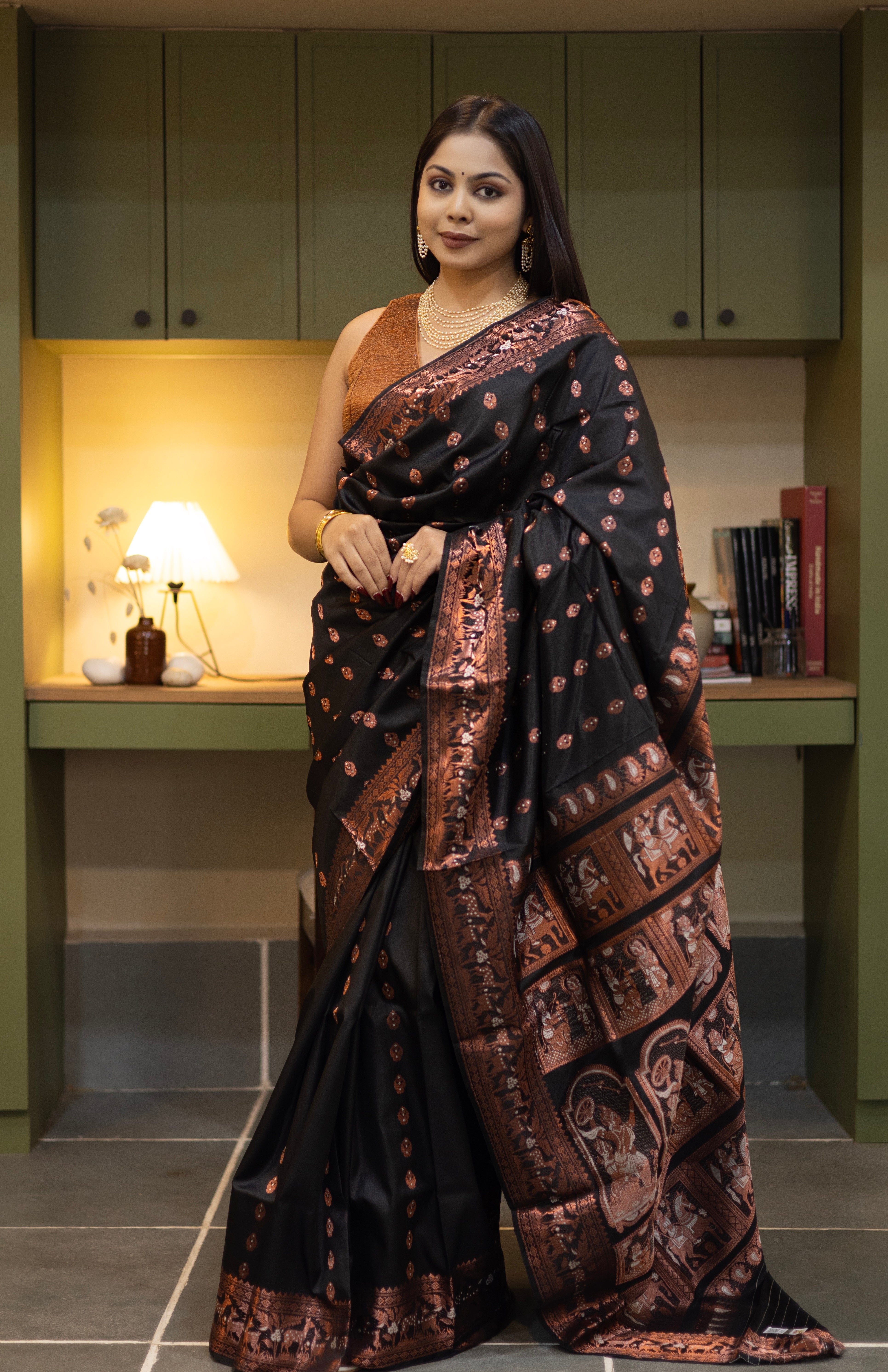 Swarnachari – Pure Silk Hazarbutta Saree

1. “Pure silk Swarnachari saree with hazarbutta thousand-motif weave and copper zari detailing for a regal look.”

2. “Silk Mark pure silk hazarbutta saree featuring intricate copper zari motifs and rich texture.” 
Woman wearing a black and copper zari saree in a room with a desk and lamp.