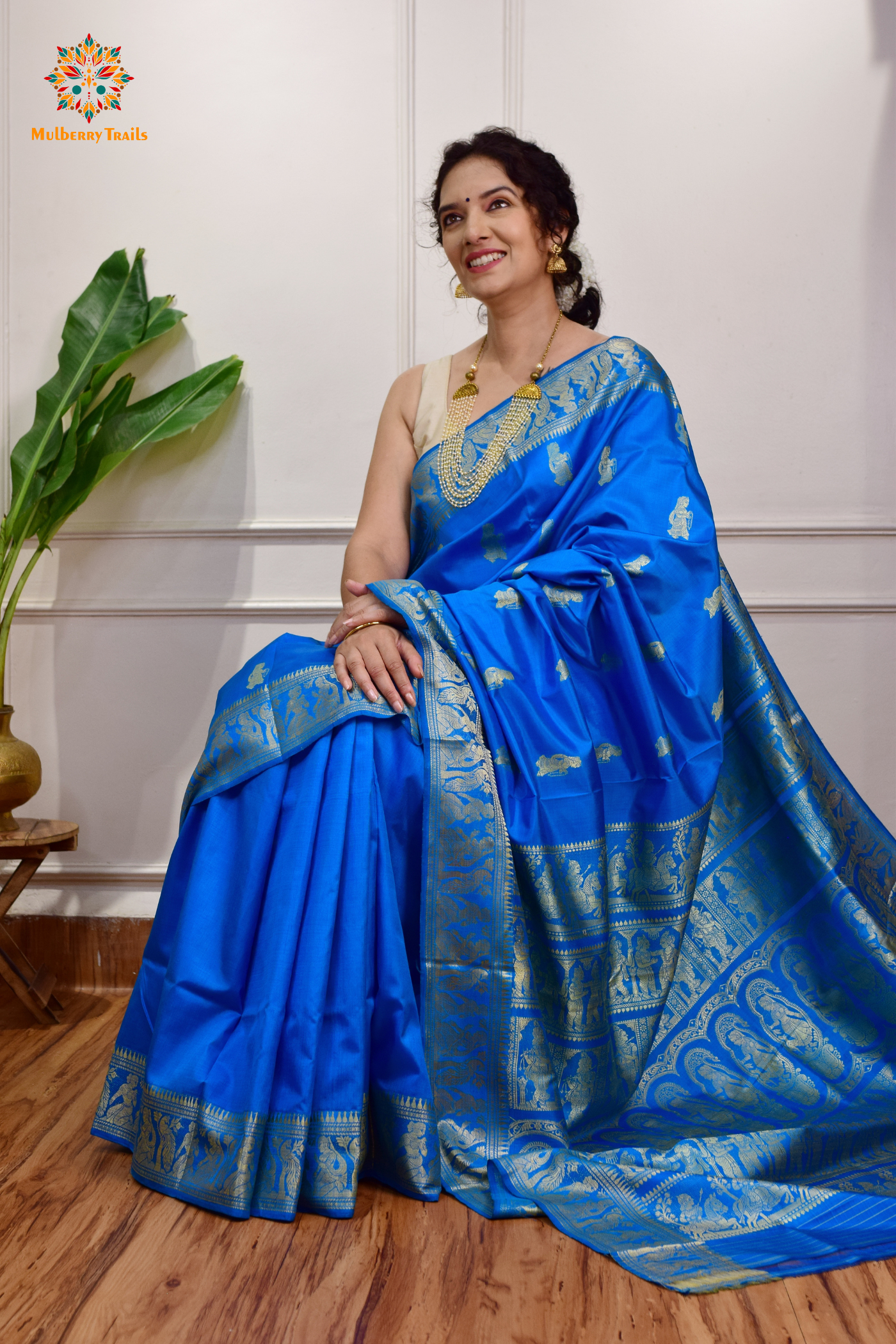 A woman wearing a Blue Baluchari Pure SIlk saree. Blue baluchari silk , bengal silk saree with deer motif on pallu and ramayan, mahabharat motifs on pallu. This is a soft pure silk saree suitable for weddings, parties, festivities. suitable for Durga Puja shopping enthusiasts and diwali festival. 