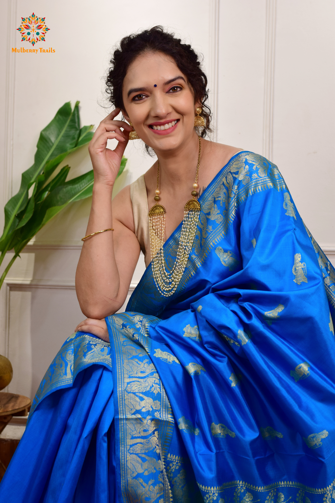 A woman wearing a Blue Baluchari Pure SIlk saree. Blue baluchari silk , bengal silk saree with deer motif on pallu and ramayan, mahabharat motifs on pallu. This is a soft pure silk saree suitable for weddings, parties, festivities. suitable for Durga Puja shopping enthusiasts and diwali festival. 