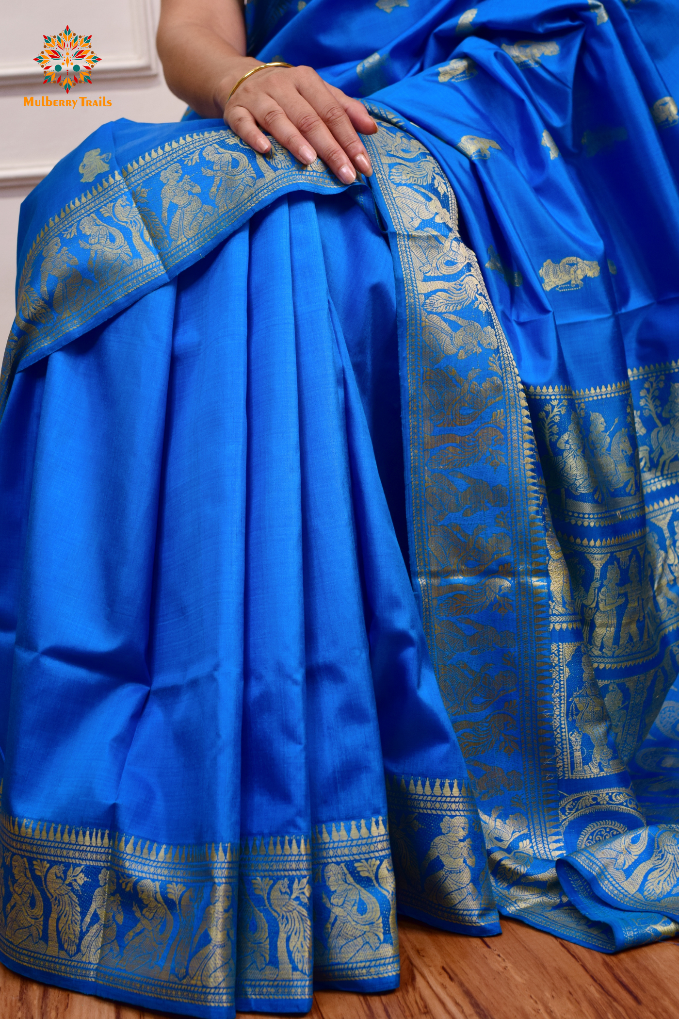 A woman wearing a Blue Baluchari Pure SIlk saree. Blue baluchari silk , bengal silk saree with deer motif on pallu and ramayan, mahabharat motifs on pallu. This is a soft pure silk saree suitable for weddings, parties, festivities. suitable for Durga Puja shopping enthusiasts and diwali festival. 