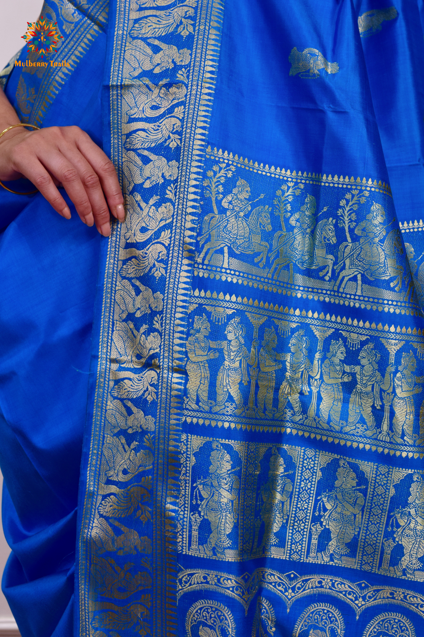 A woman wearing a Blue Baluchari Pure SIlk saree. Blue baluchari silk , bengal silk saree with deer motif on pallu and ramayan, mahabharat motifs on pallu. This is a soft pure silk saree suitable for weddings, parties, festivities. suitable for Durga Puja shopping enthusiasts and diwali festival. 