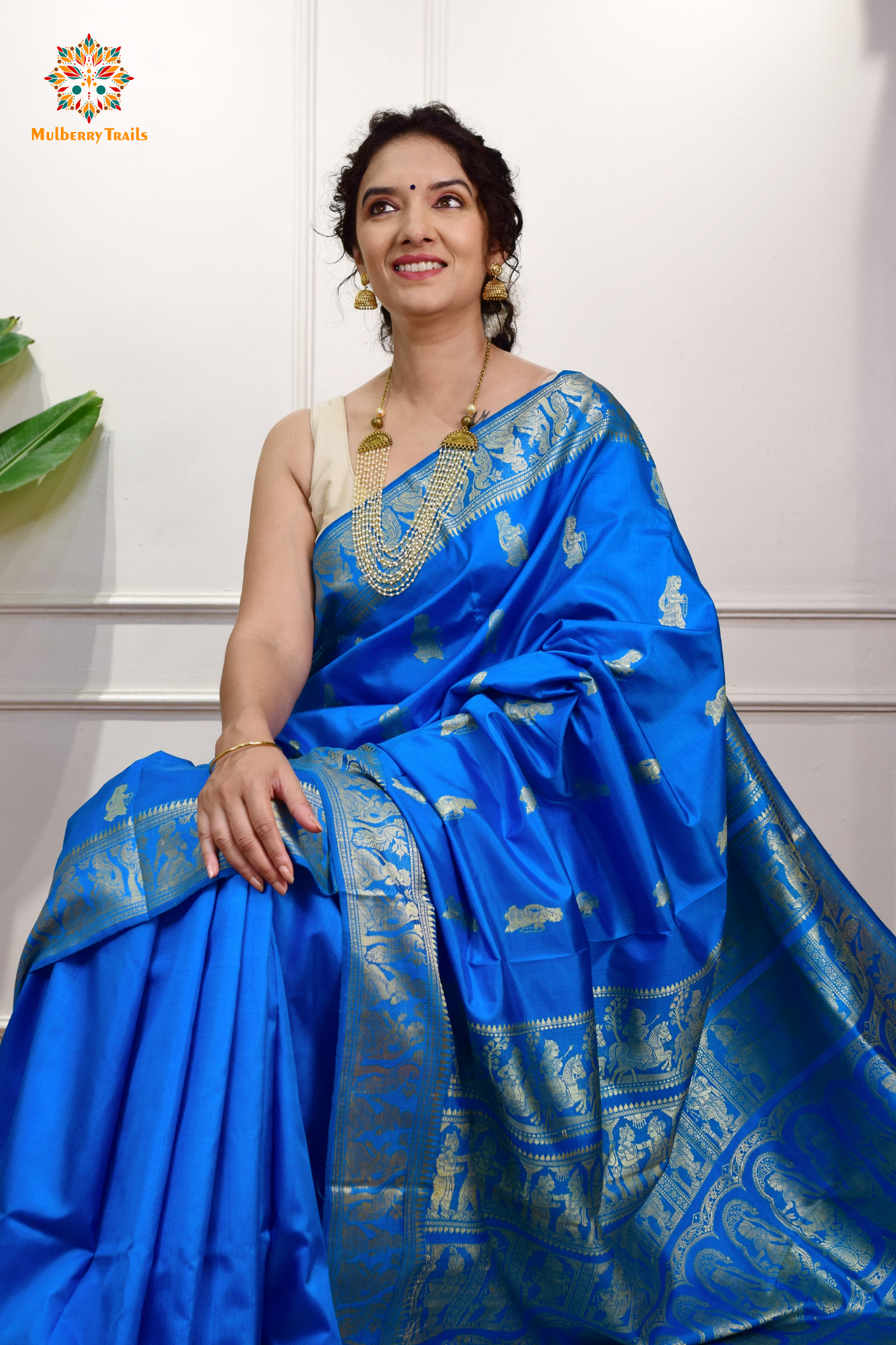 A woman wearing a Blue Baluchari Pure SIlk saree. Blue baluchari silk , bengal silk saree with deer motif on pallu and ramayan, mahabharat motifs on pallu. This is a soft pure silk saree suitable for weddings, parties, festivities. suitable for Durga Puja shopping enthusiasts and diwali festival. 