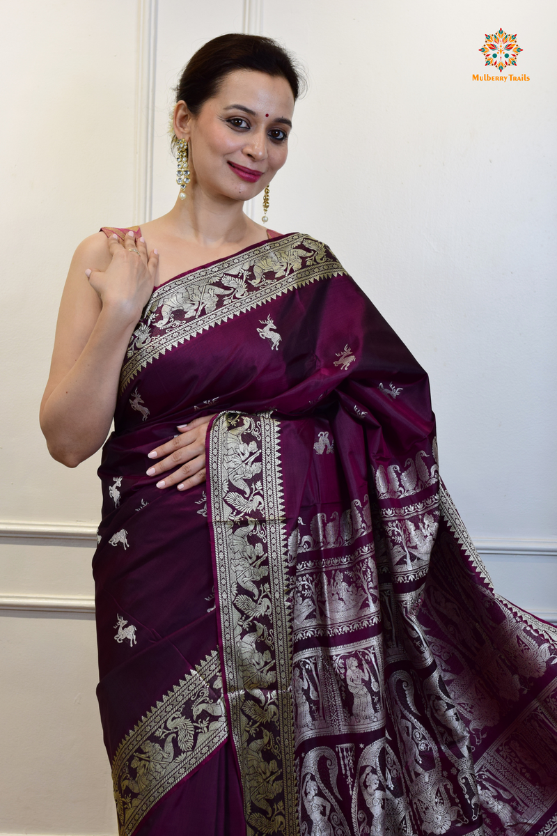 A woman wearing a Purple Baluchari Pure SIlk saree. Purple baluchari silk , bengal silk saree with deer motif on pallu and ramayan, mahabharat motifs on pallu. This is a soft pure silk saree suitable for weddings, parties, festivities. suitable for Durga Puja shopping enthusiasts and diwali festival. 