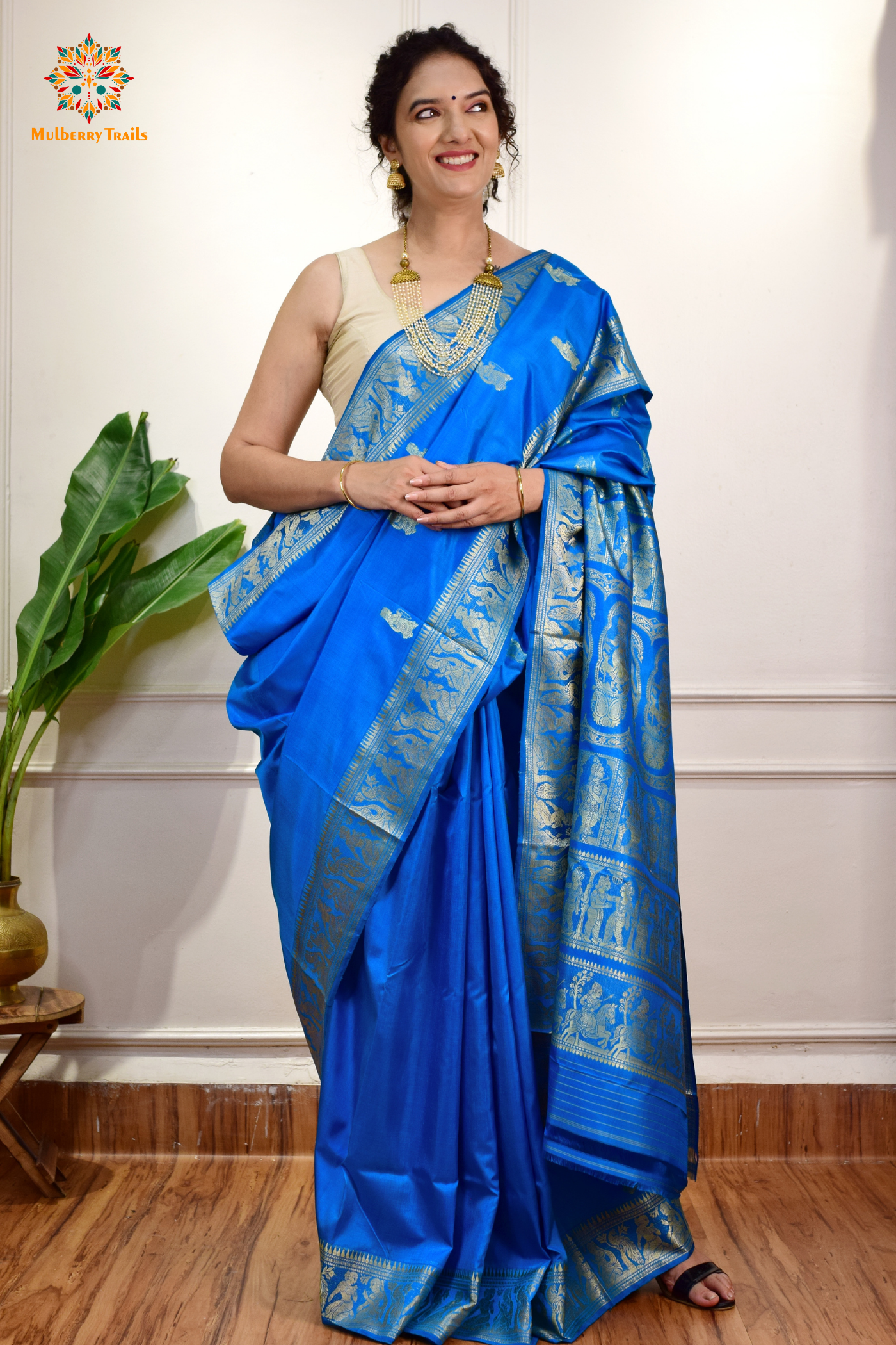 A woman wearing a Blue Baluchari Pure SIlk saree. Blue baluchari silk , bengal silk saree with deer motif on pallu and ramayan, mahabharat motifs on pallu. This is a soft pure silk saree suitable for weddings, parties, festivities. suitable for Durga Puja shopping enthusiasts and diwali festival. 