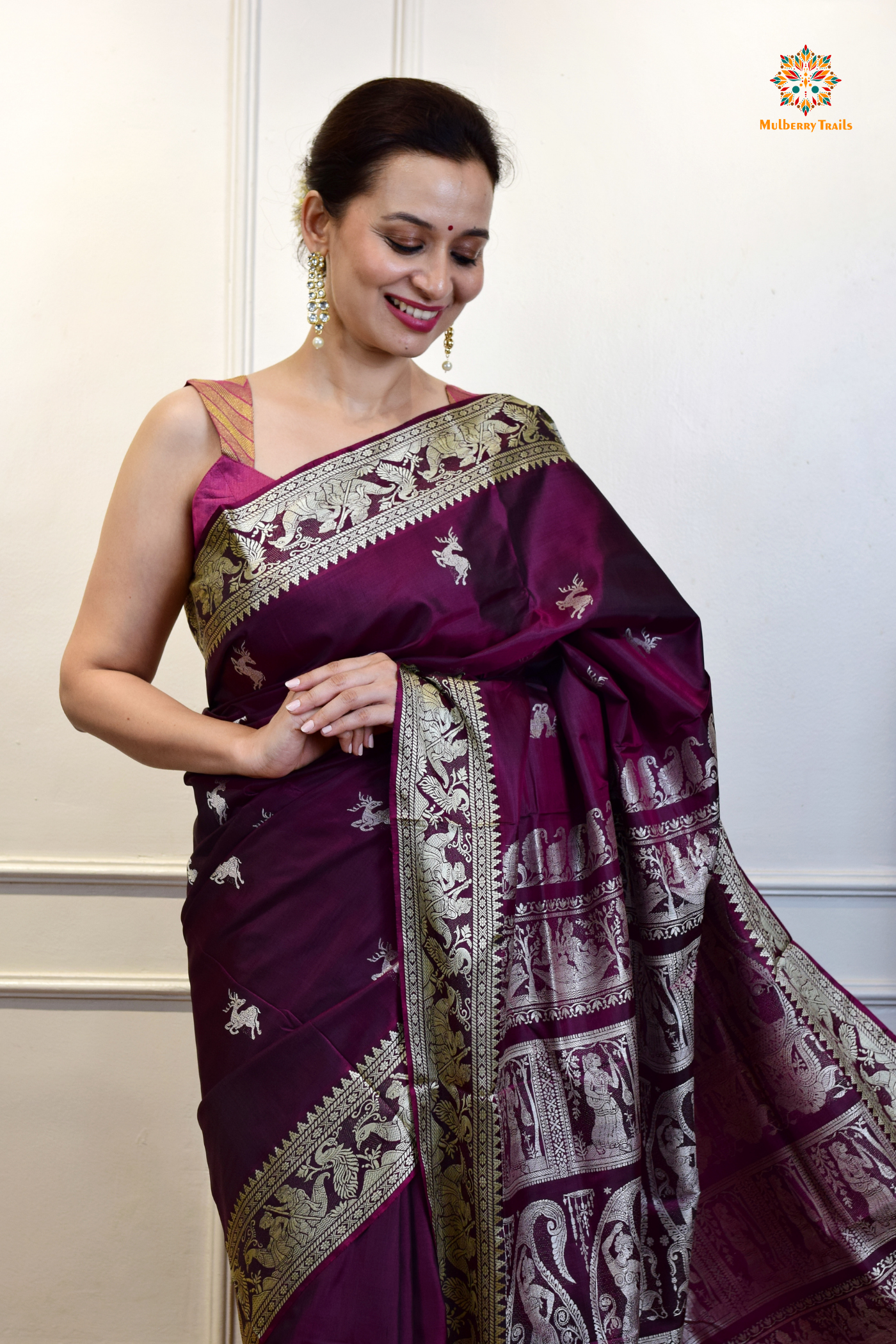 A woman wearing a Purple Baluchari Pure SIlk saree. Purple baluchari silk , bengal silk saree with deer motif on pallu and ramayan, mahabharat motifs on pallu. This is a soft pure silk saree suitable for weddings, parties, festivities. suitable for Durga Puja shopping enthusiasts and diwali festival. 