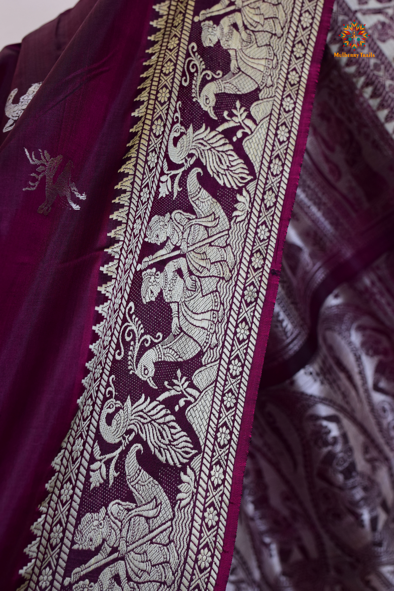 A woman wearing a Purple Baluchari Pure SIlk saree. Purple baluchari silk , bengal silk saree with deer motif on pallu and ramayan, mahabharat motifs on pallu. This is a soft pure silk saree suitable for weddings, parties, festivities. suitable for Durga Puja shopping enthusiasts and diwali festival. 