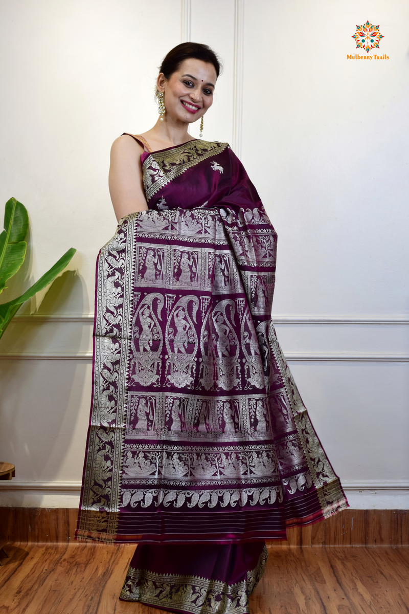 A woman wearing a Purple Baluchari Pure SIlk saree. Purple baluchari silk , bengal silk saree with deer motif on pallu and ramayan, mahabharat motifs on pallu. This is a soft pure silk saree suitable for weddings, parties, festivities. suitable for Durga Puja shopping enthusiasts and diwali festival. 