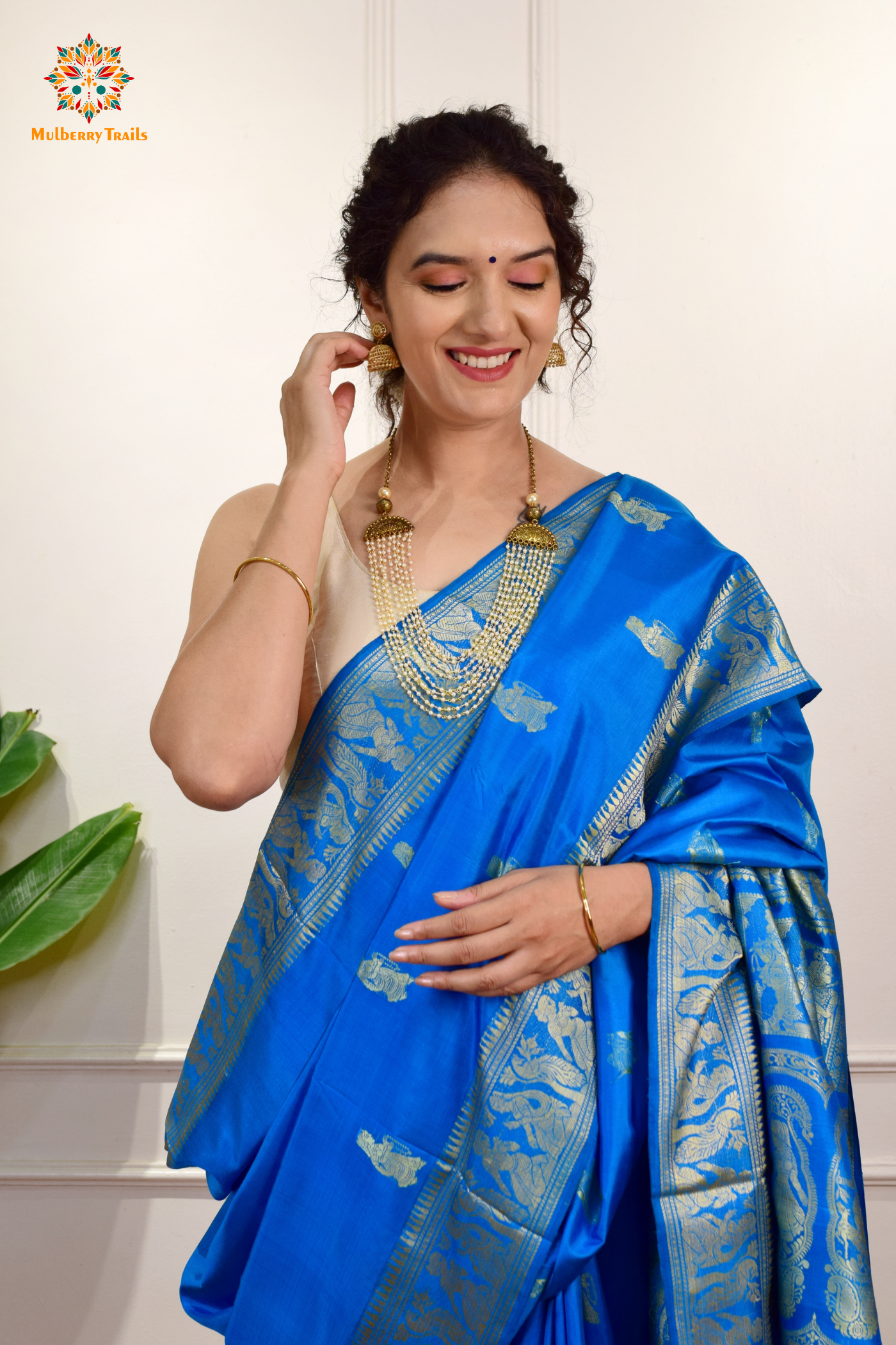 A woman wearing a Blue Baluchari Pure SIlk saree. Blue baluchari silk , bengal silk saree with deer motif on pallu and ramayan, mahabharat motifs on pallu. This is a soft pure silk saree suitable for weddings, parties, festivities. suitable for Durga Puja shopping enthusiasts and diwali festival. 