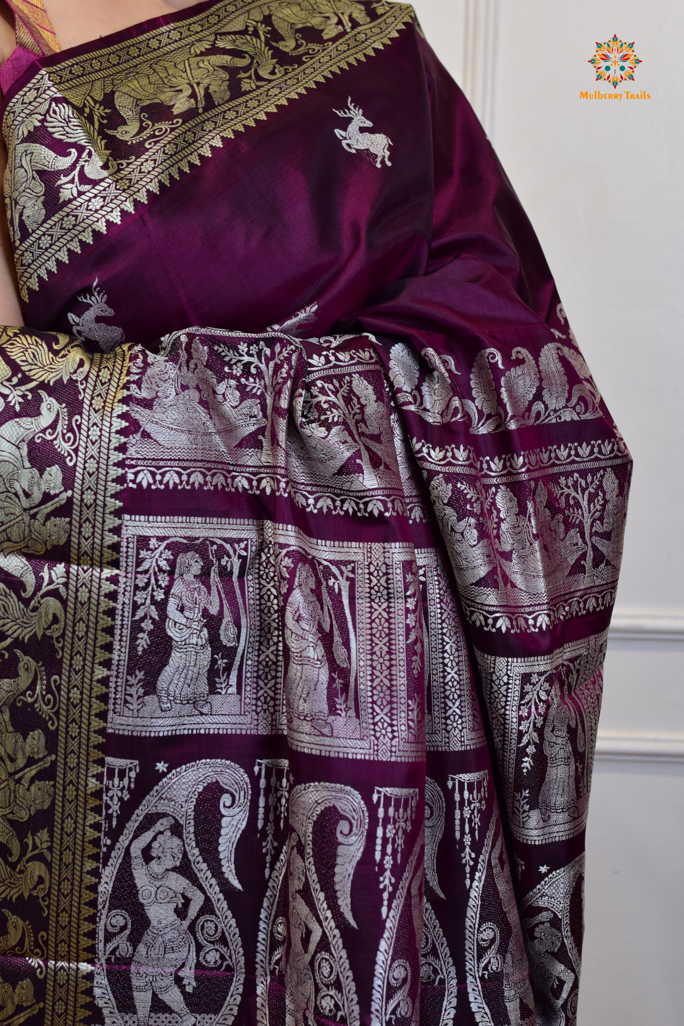 A woman wearing a Purple Baluchari Pure SIlk saree. Purple baluchari silk , bengal silk saree with deer motif on pallu and ramayan, mahabharat motifs on pallu. This is a soft pure silk saree suitable for weddings, parties, festivities. suitable for Durga Puja shopping enthusiasts and diwali festival. 