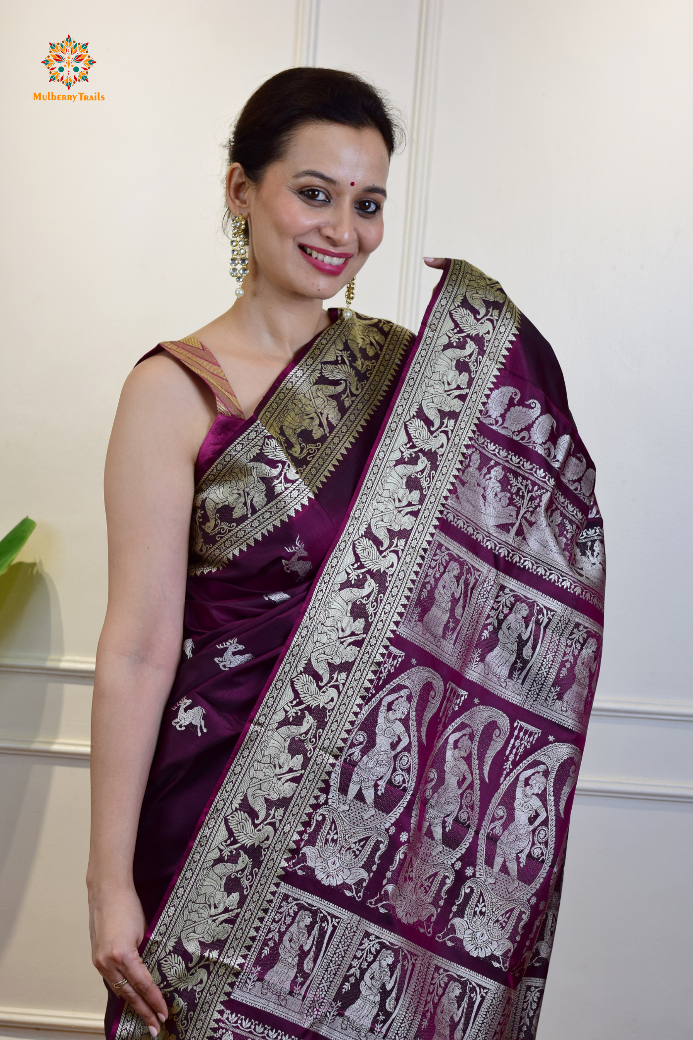 A woman wearing a Purple Baluchari Pure SIlk saree. Purple baluchari silk , bengal silk saree with deer motif on pallu and ramayan, mahabharat motifs on pallu. This is a soft pure silk saree suitable for weddings, parties, festivities. suitable for Durga Puja shopping enthusiasts and diwali festival. 