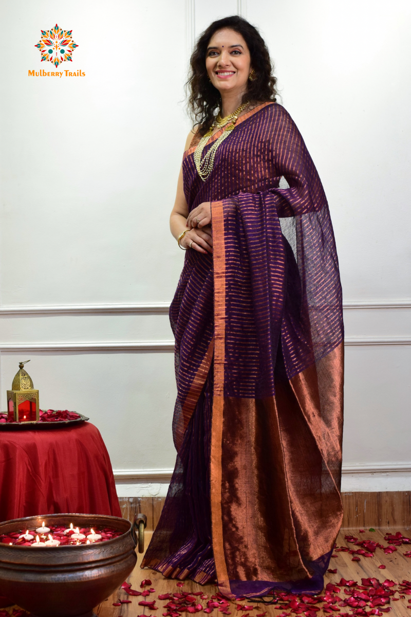 Woman celebrating Indian Festivals draped in Premium Handwoven Linen Saree / Sari. Comfortable and contemporary design of sari is perfect for attending weddings or festivals. Premium saree for festivals, sophisticated saree, Luxury contemporary sari linen saree, handloom, stripes, tissue, unique copper zari work border, Model wearing Linen sari, Saree and blouse combination, saree for friends wedding, saree for wedding gift, saree for festive wear, sari for ganpati occassion, saree for diwali