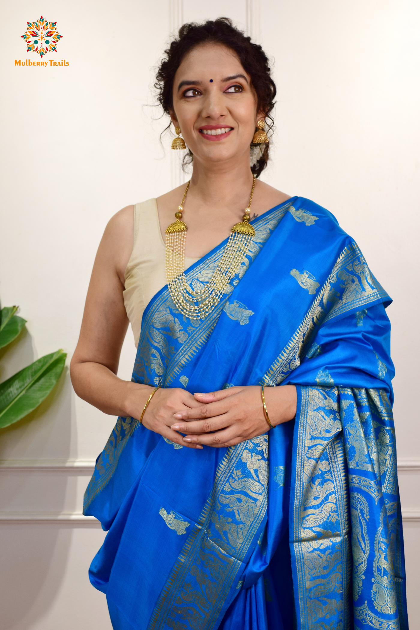 A woman wearing a Blue Baluchari Pure SIlk saree. Blue baluchari silk , bengal silk saree with deer motif on pallu and ramayan, mahabharat motifs on pallu. This is a soft pure silk saree suitable for weddings, parties, festivities. suitable for Durga Puja shopping enthusiasts and diwali festival. 