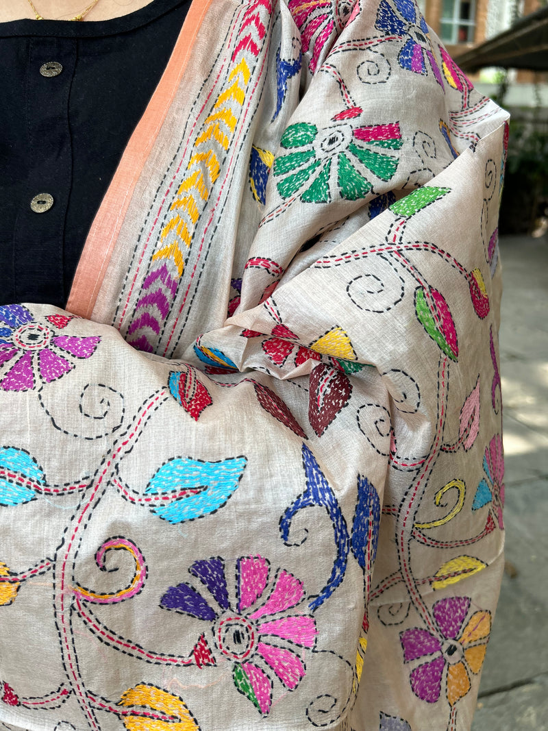 Elegant pure silk dupatta in beige color, featuring intricate Kantha embroidery with vibrant floral and paisley motifs. The dupatta boasts a luxurious sheen and a rich texture, perfect for adding a touch of sophistication to any outfit. The hand-embroidered details highlight the traditional craftsmanship and artistry, making it a statement accessory for festive occasions or special events.