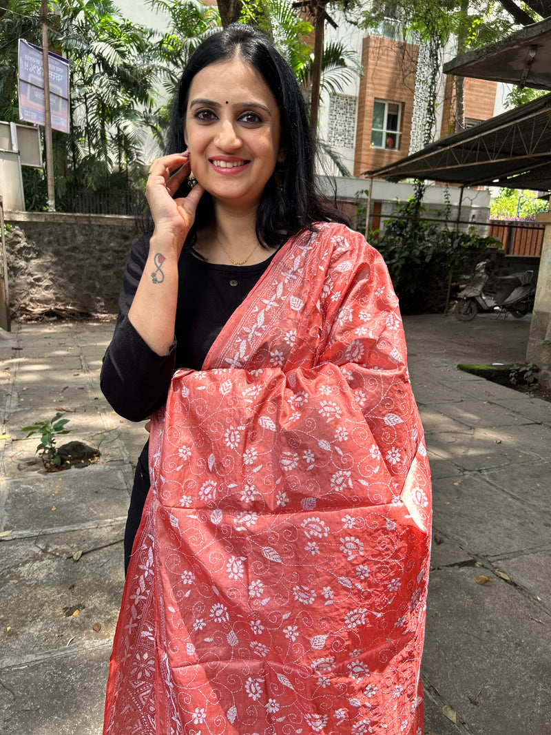 Elegant pure silk dupatta in peach Orange color, featuring intricate Kantha embroidery with vibrant floral and paisley motifs. The dupatta boasts a luxurious sheen and a rich texture, perfect for adding a touch of sophistication to any outfit. The hand-embroidered details highlight the traditional craftsmanship and artistry, making it a statement accessory for festive occasions or special events.